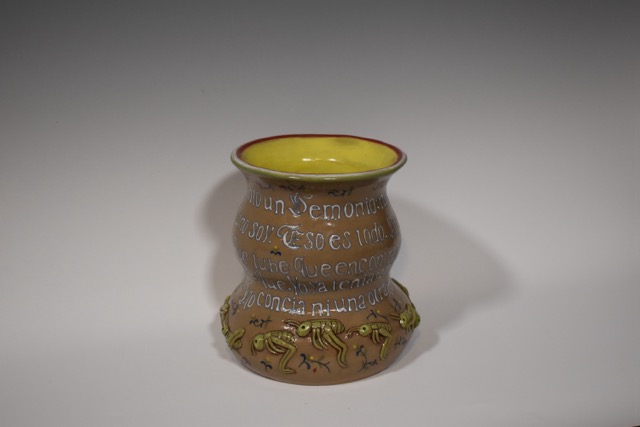 Colorful ceramic vase with yellow interior and decorative patterns, placed on a plain background.