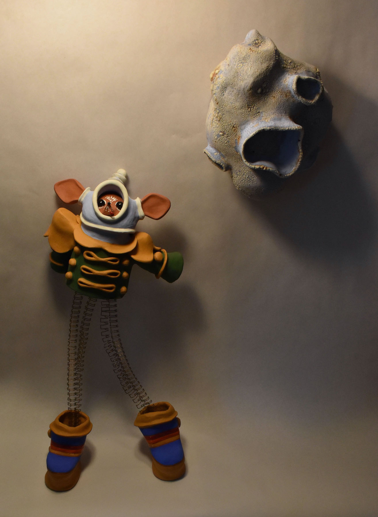 Toy figure with a round face, striped clothing, and colorful limbs, lying on a flat surface next to a skull.