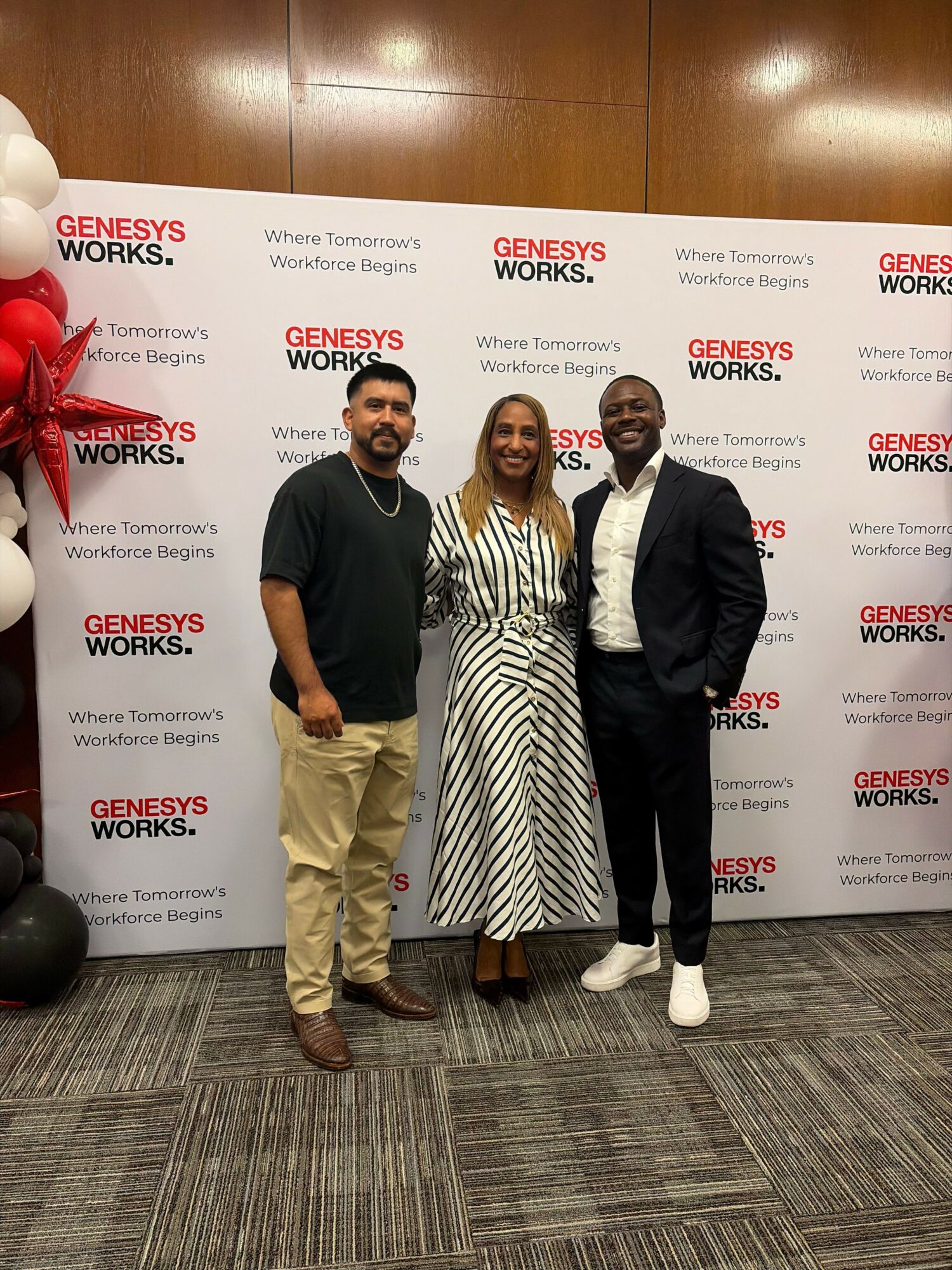 Three people standing in front of a backdrop with 'GUERNSEYS WORKS' logo, posing for a photo indoors.