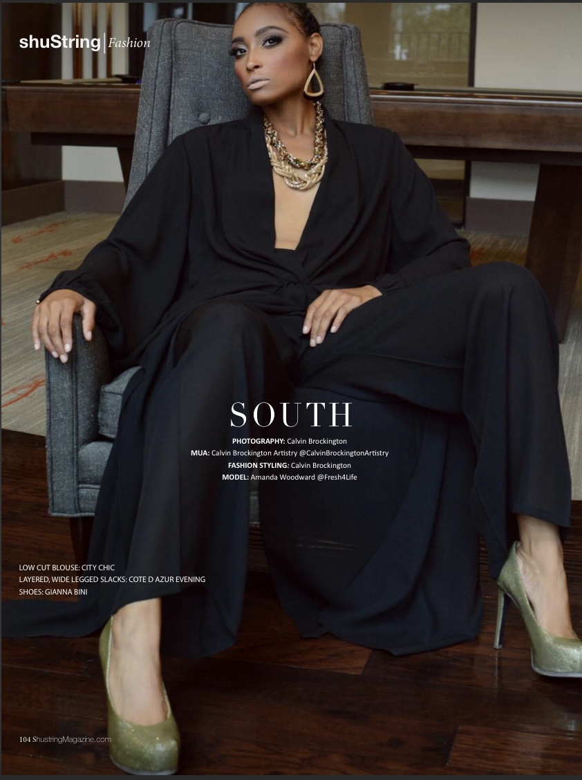 Woman in black outfit sitting on a chair with a wooden table behind her, wearing jewelry and high heels.