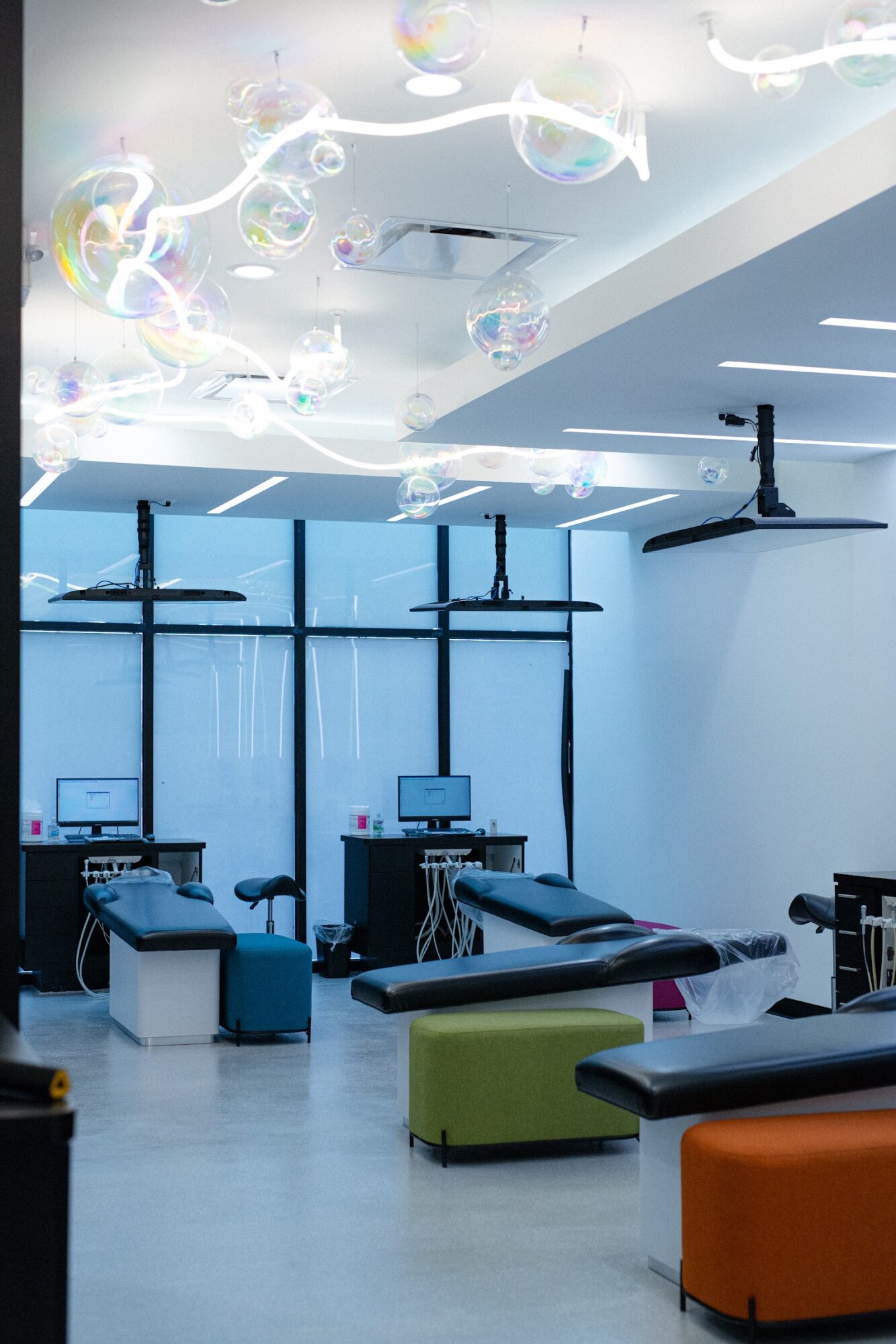 Medical or dental office with chairs, equipment, and large windows, ceiling lights, and a decorative ceiling fixture.