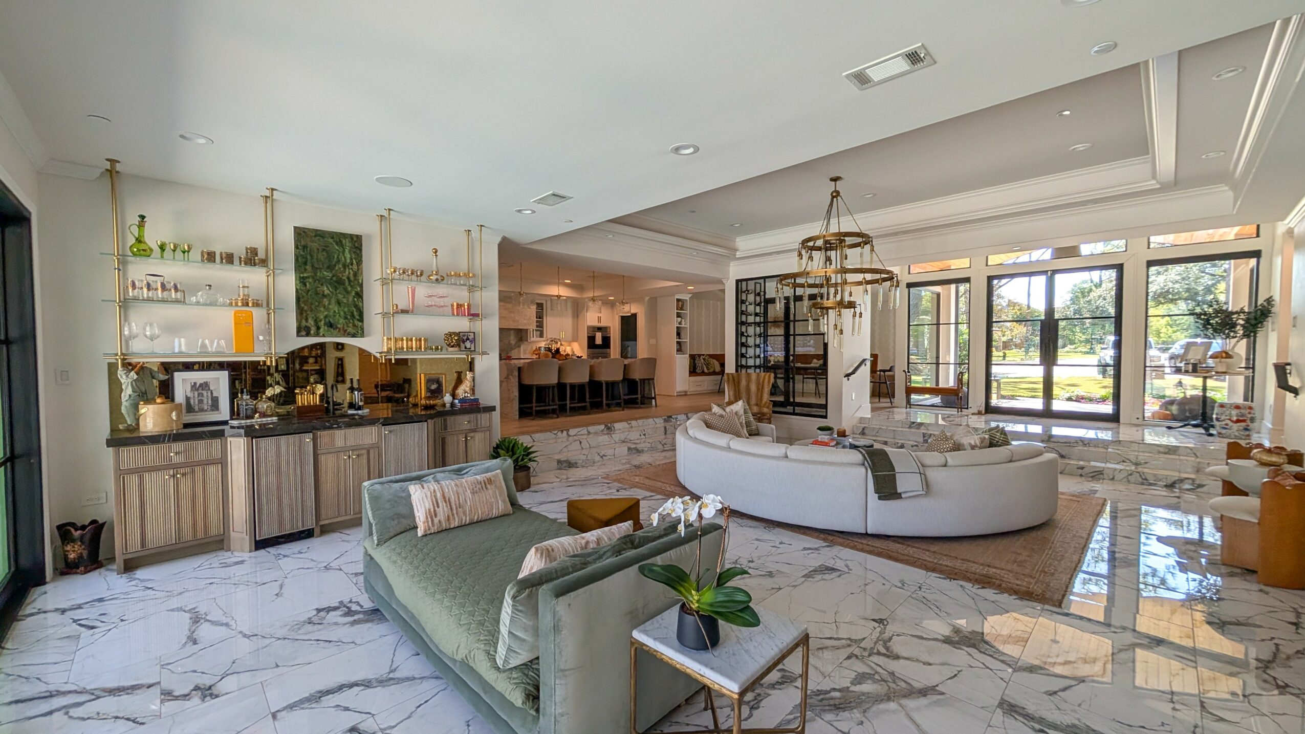 Spacious living room with marble floors, large windows, and modern furniture, including a curved sofa and a green armchair.