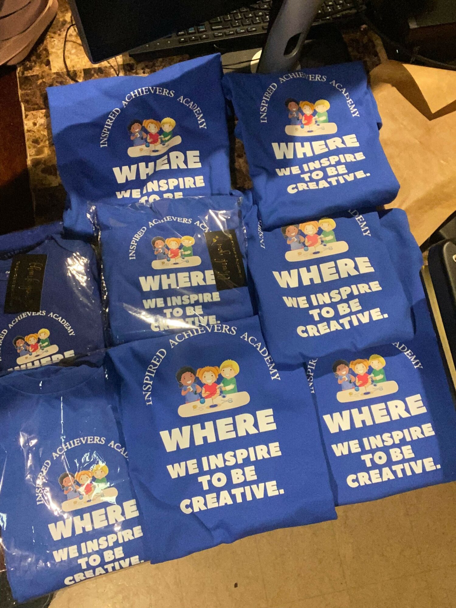 Multiple blue bags with white text and a colorful logo, placed on a table surface.