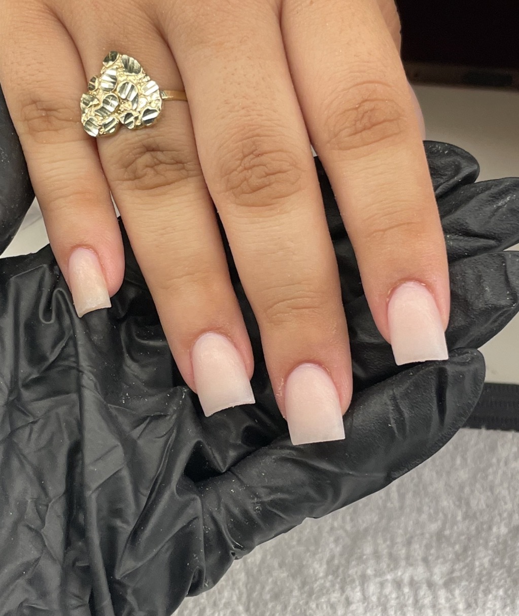 Hand with a ring on the ring finger, displaying long, natural nails, resting on a black glove.
