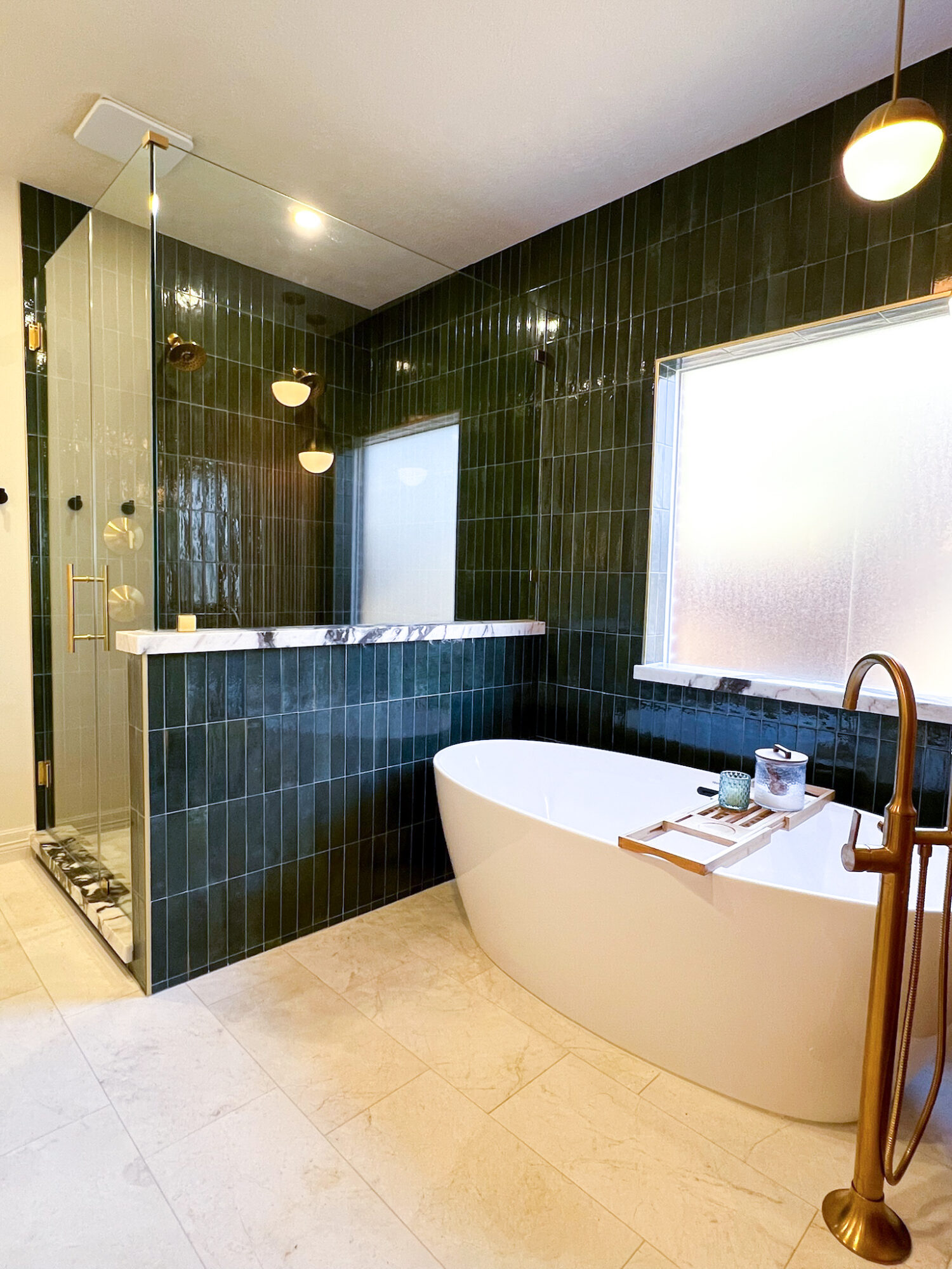 Modern bathroom with black tiled walls, a freestanding bathtub, and a glass shower enclosure, illuminated by natural and artificial light.
