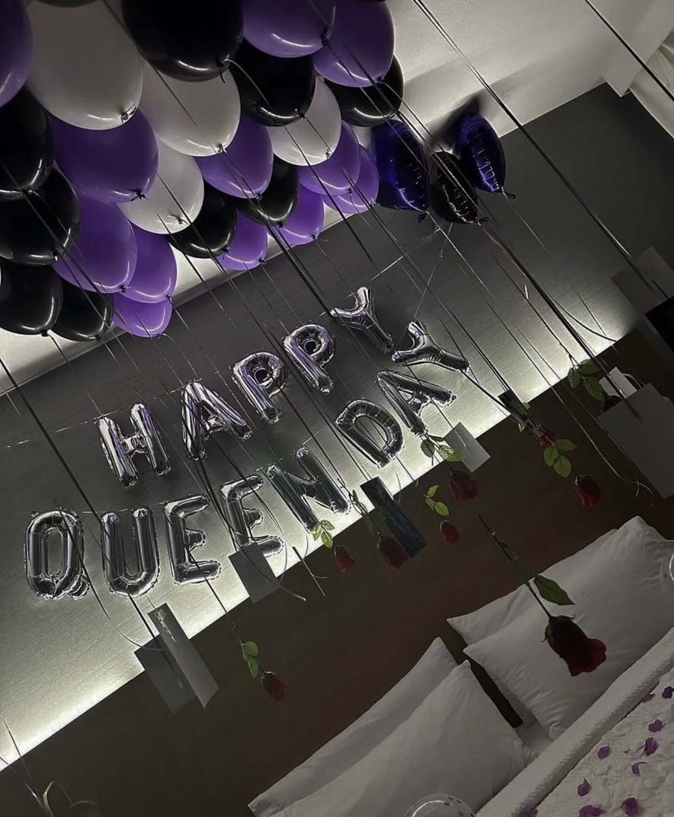 Decorations with balloons and a banner reading 'HAPPY QUEEN DAY' in a room, with tables and chairs visible.
