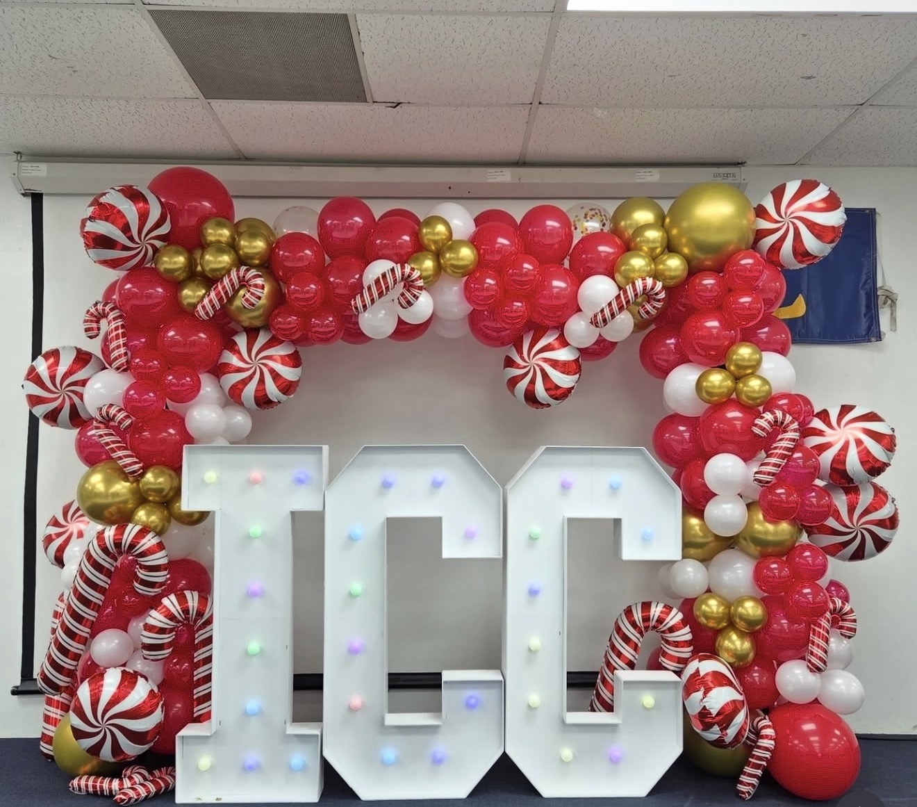 Large white number '10' decorated with colorful balloons, including red, white, gold, and peppermint-striped balloons, on a wall.