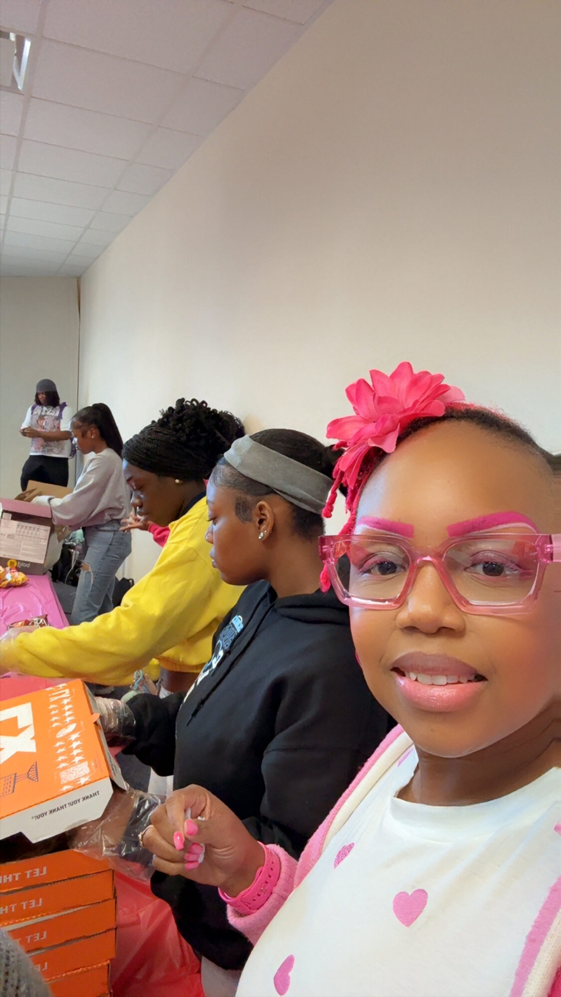 Group of young girls sitting at a table with books and supplies, some wearing glasses and headbands, in a classroom.