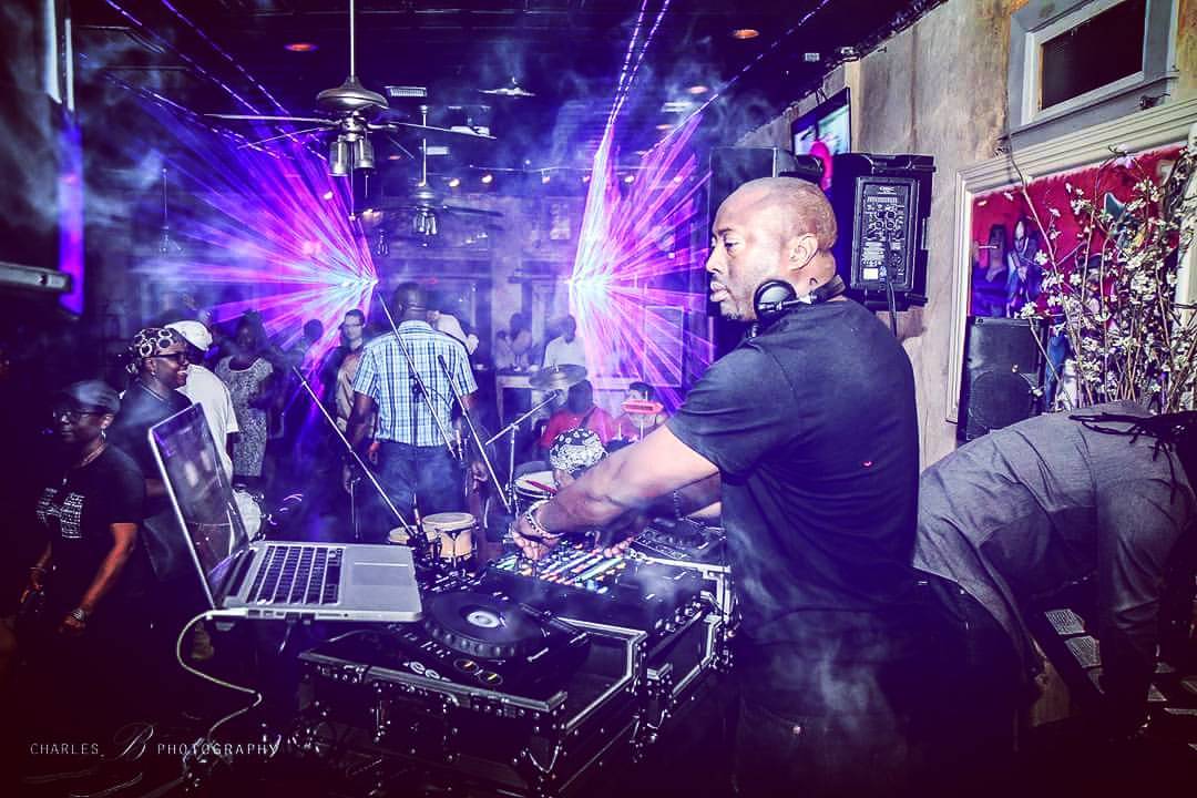 DJ with headphones at turntables in a club with colorful lights and dancing crowd, vibrant atmosphere, electronic music scene.