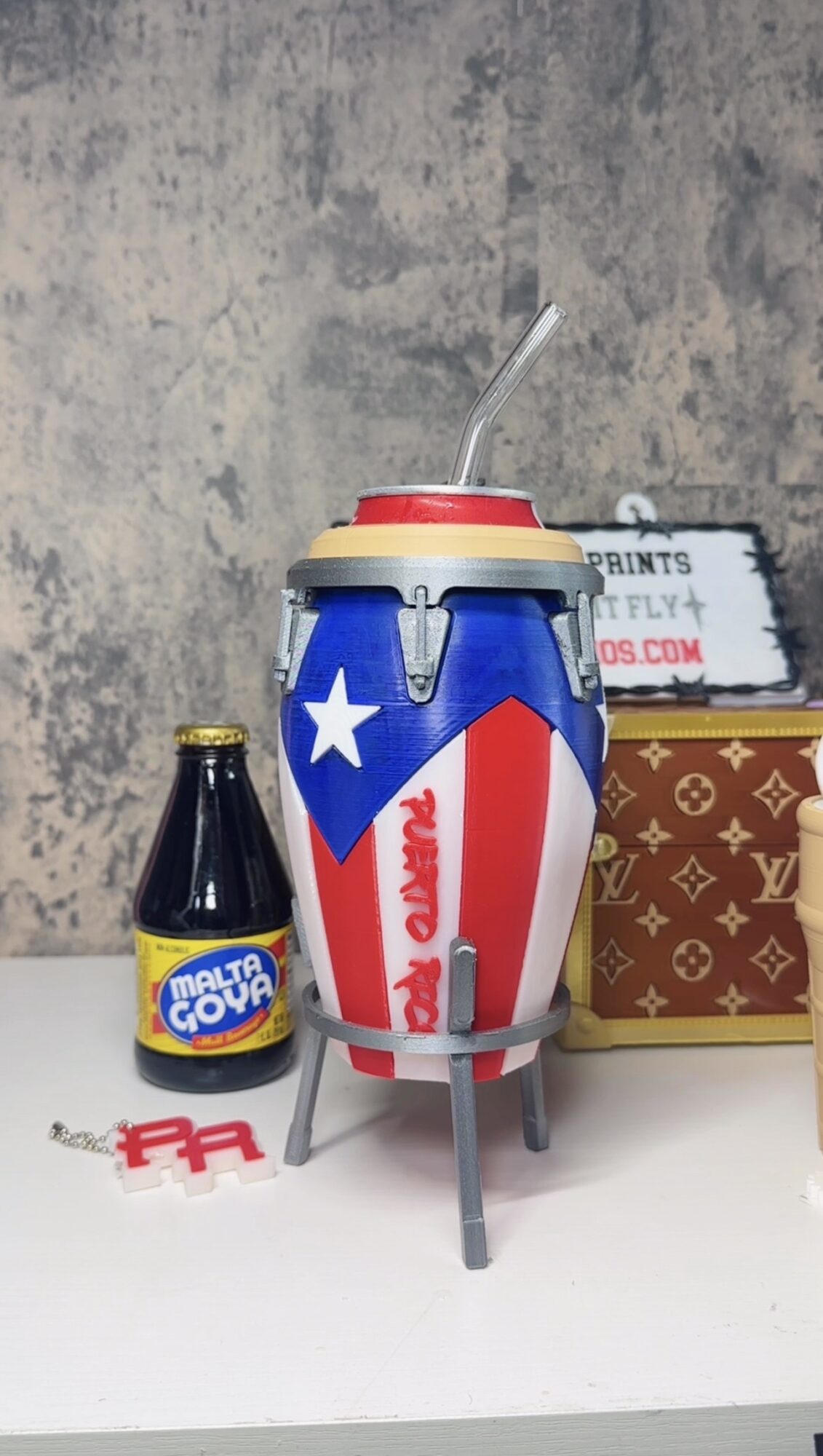A small retro-style popcorn machine with a patriotic design, a bottle of caramel syrup, and a red plastic fork on a white surface.
