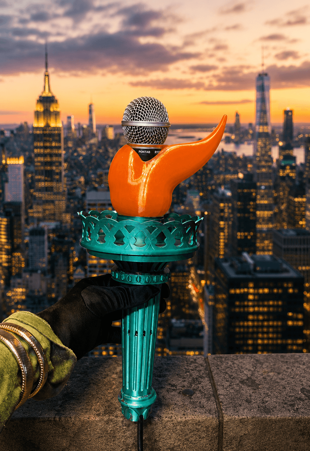A microphone on a stand with an orange and teal decorative cover, city skyline at sunset in background.