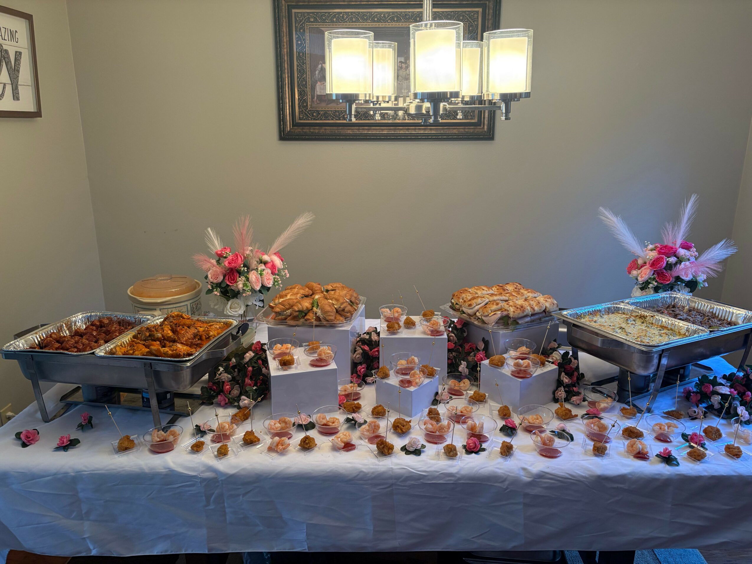 Table with desserts, flowers, and plates, viewed upside down, with a framed picture on a light-colored wall behind.