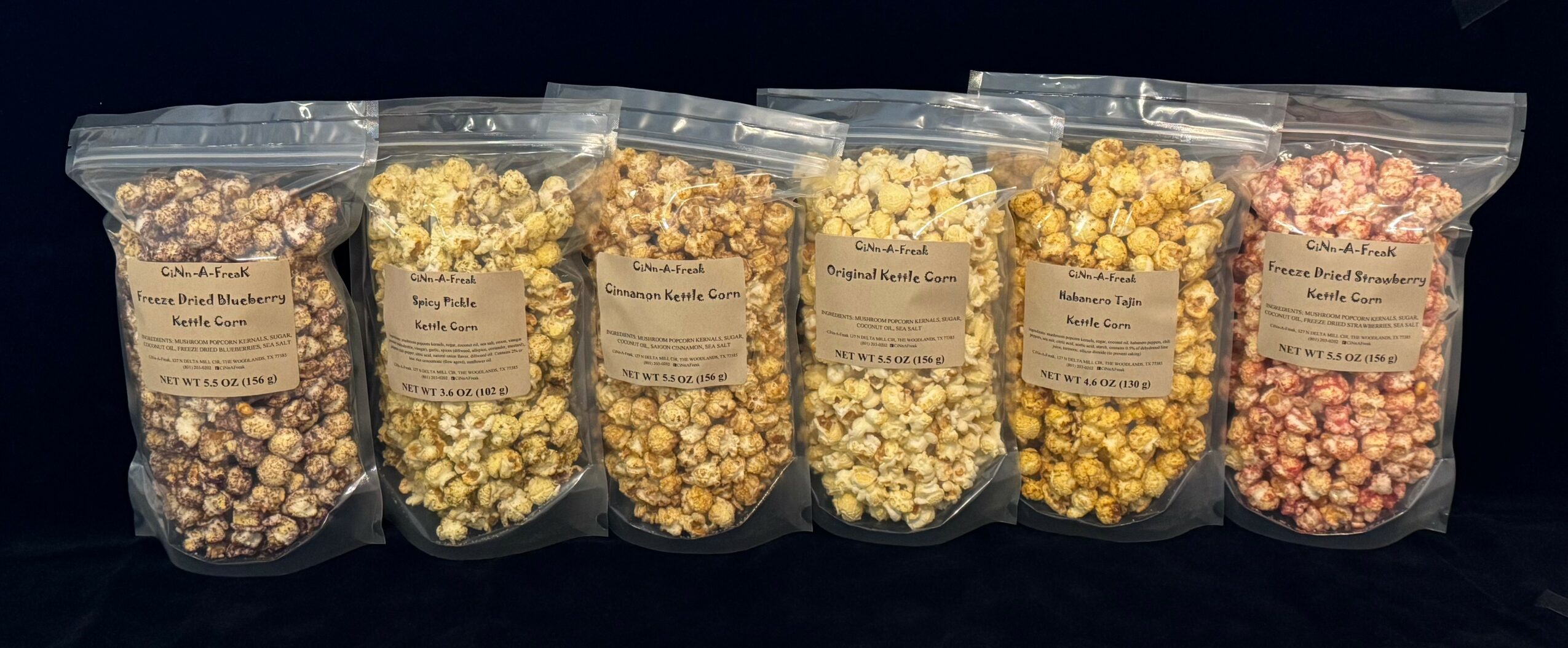 Five clear plastic bags filled with different types of popcorn, labeled, against a dark background.