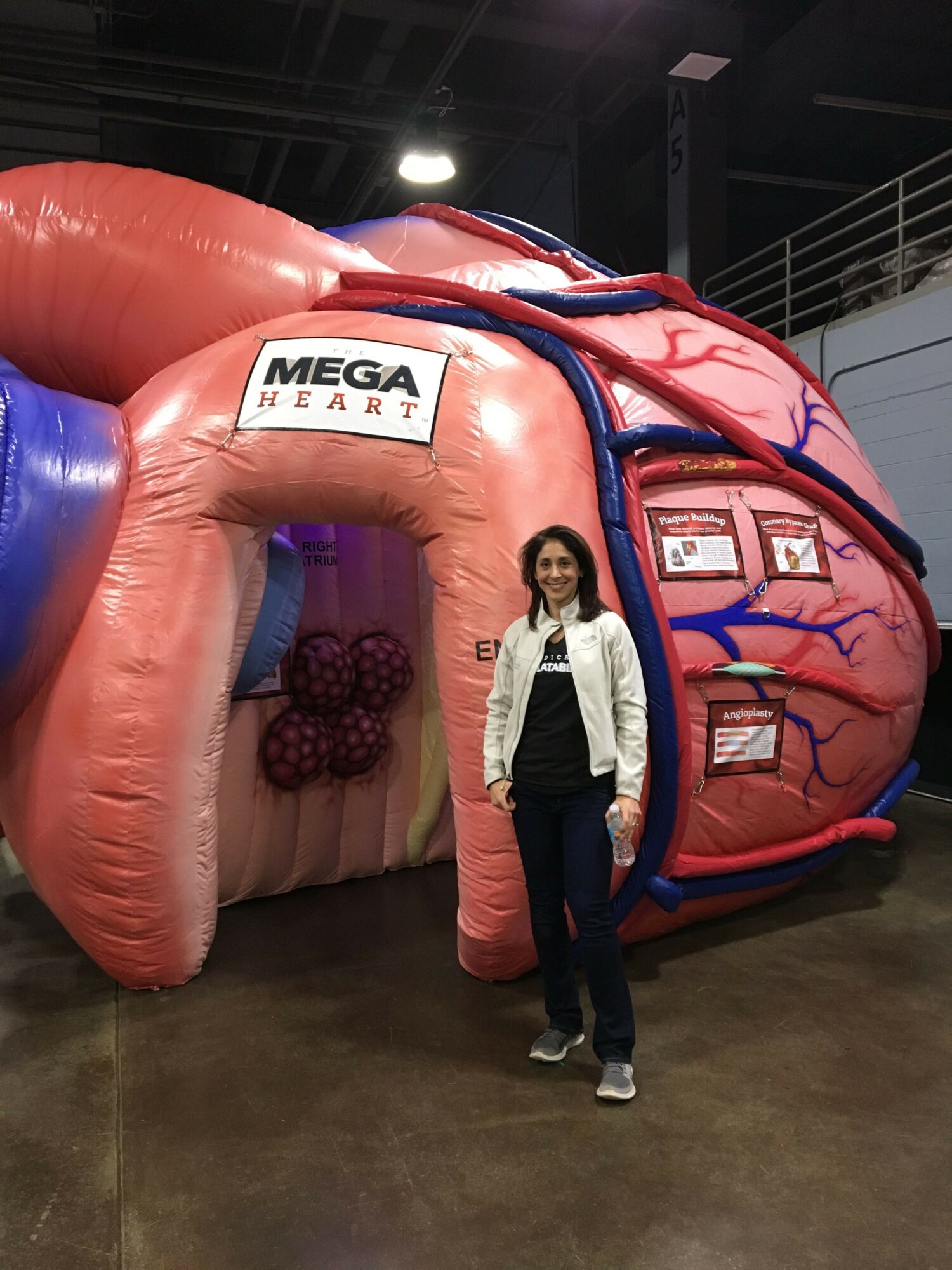 Person standing next to a large pink and blue inflatable structure with a sign that reads 'MEGA'.