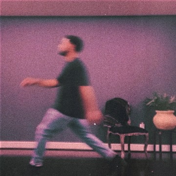 Person walking past a wall with chairs and potted plants, blurred motion, indoor setting.