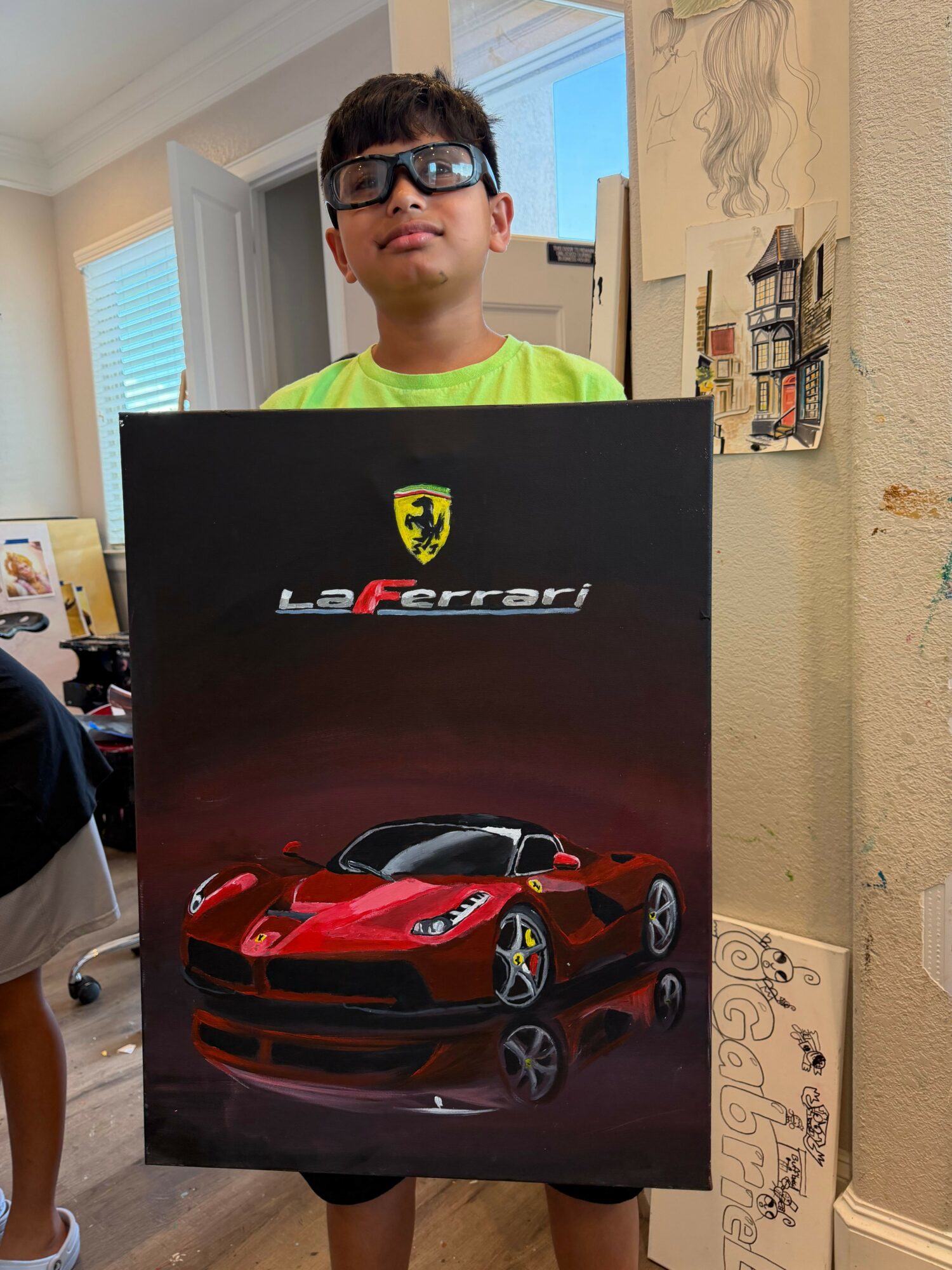 Person with glasses and dark hair in a bright room holding a Ferrari LeFerrari poster featuring a red sports car.