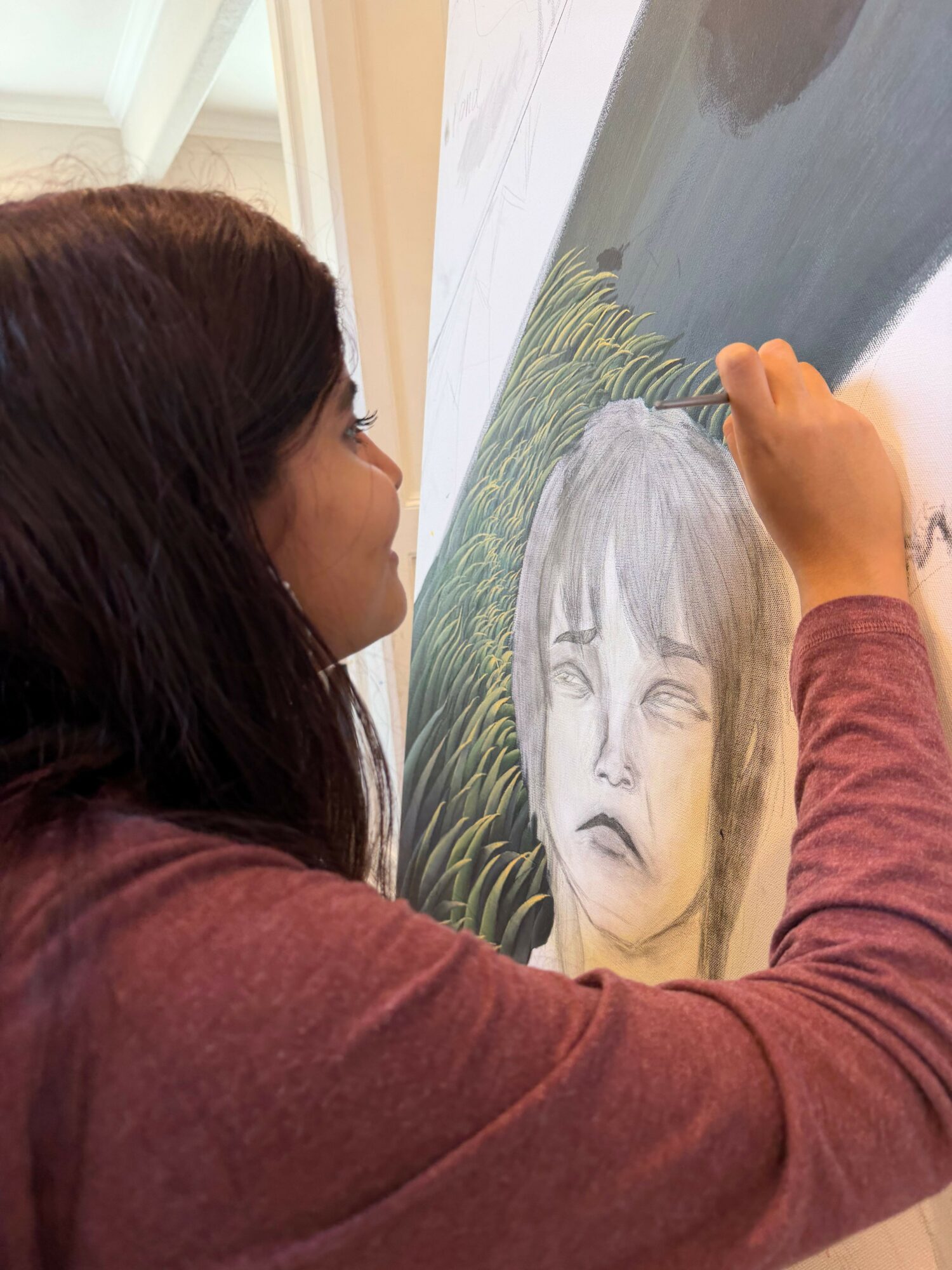 Person with long dark hair looking at a large painting of a woman with long hair and a serene expression.