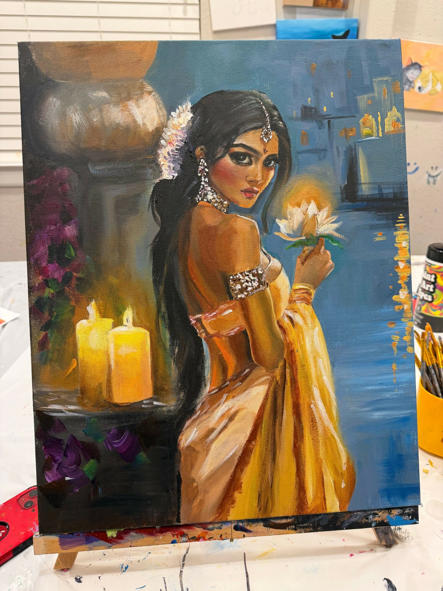 A woman in traditional attire holding a lit candle, with a cityscape background and candles in the foreground.