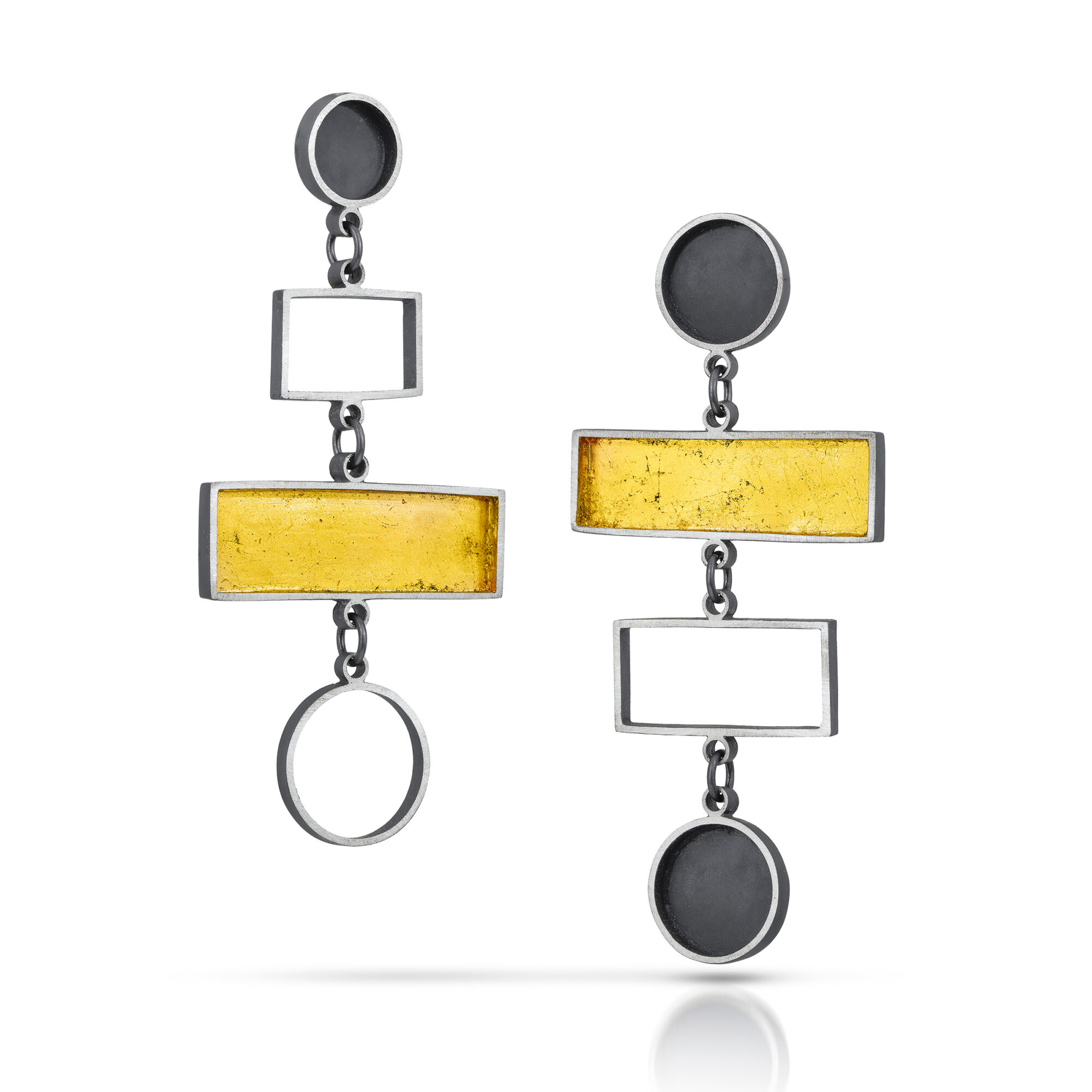 Pair of geometric earrings with black circles, yellow rectangles, and white rectangles, hanging vertically. Bright background.