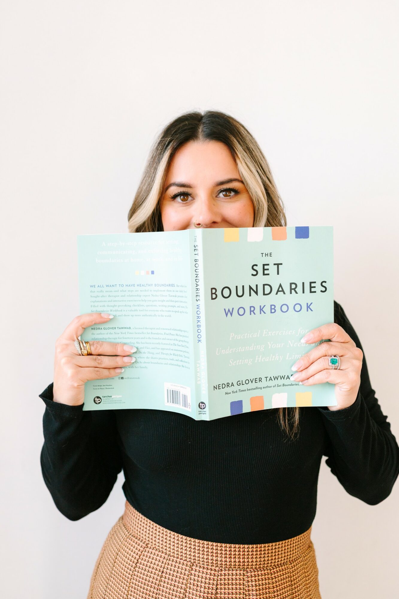 Woman holding a workbook titled 'Set Boundaries Workbook' in front of her face, smiling, against a white background.