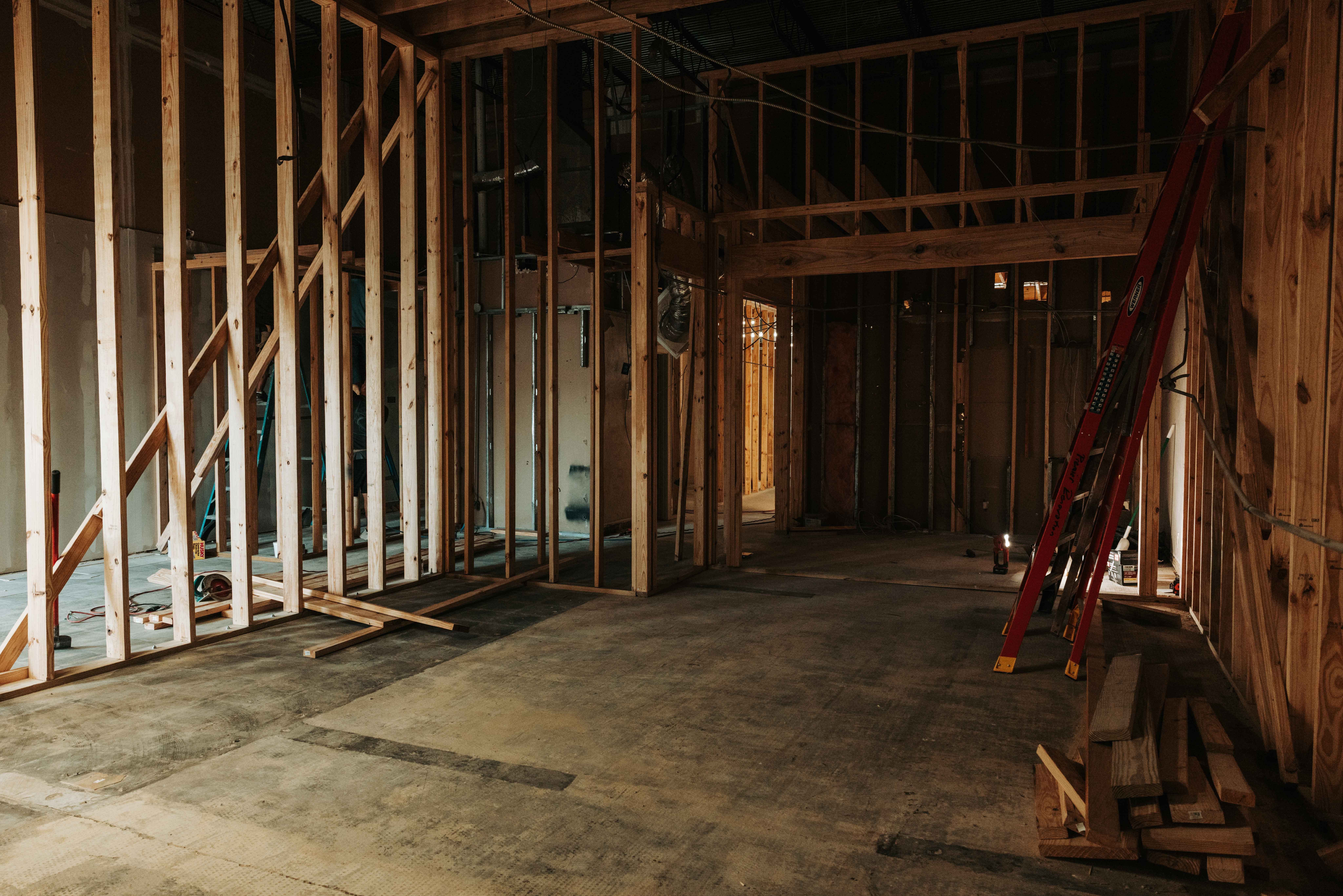 Construction site with wooden framing and a ladder leaning against the wall, unfinished interior space.
