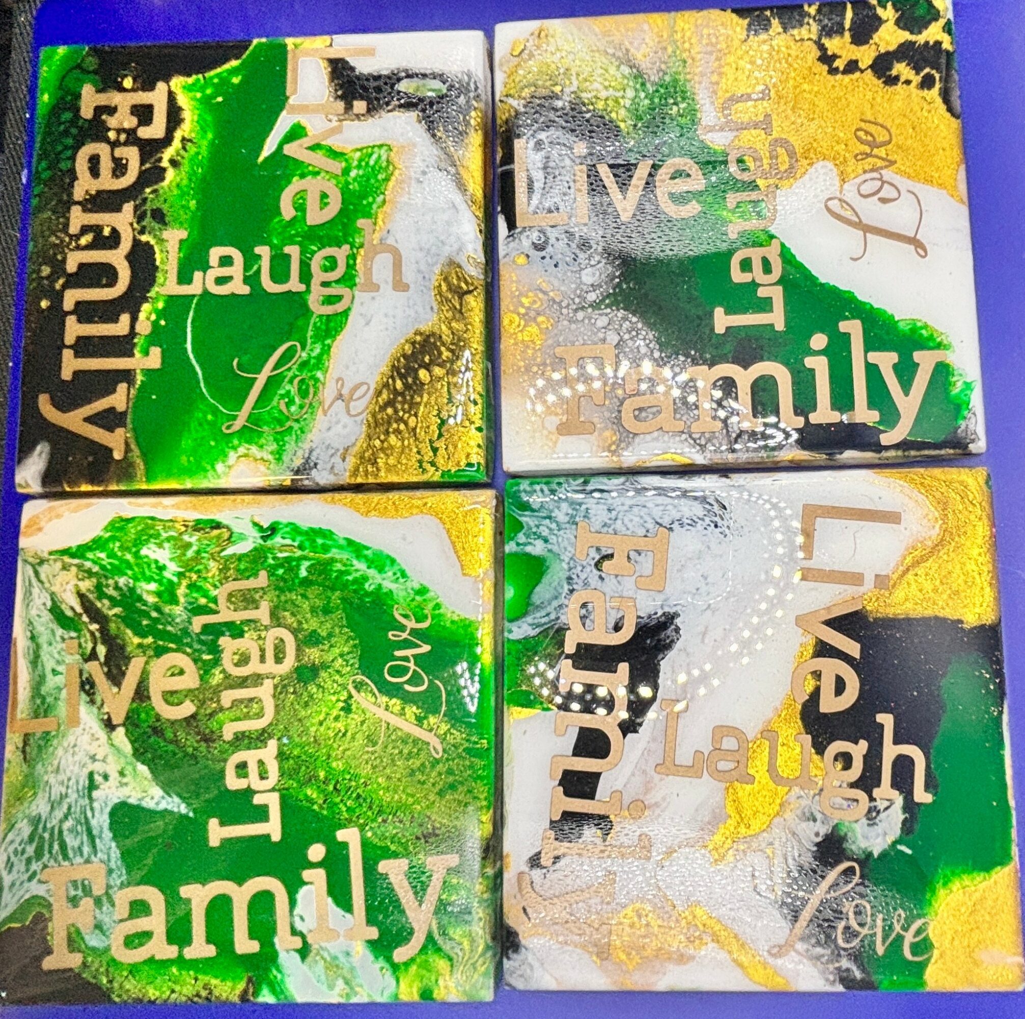 Four colorful square tiles with words like 'Family,' 'Love,' 'Laugh,' and 'Live,' decorated with green, yellow, and black paint splashes.