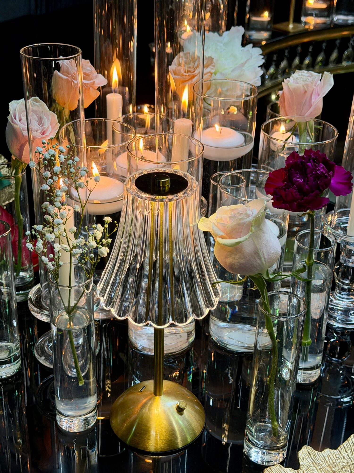 Elegant table setting with flowers, candles, and a small lamp, creating a warm, festive atmosphere.