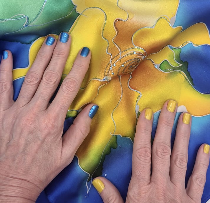 Two hands with painted nails touch a colorful abstract puzzle with yellow, blue, and green sections.
