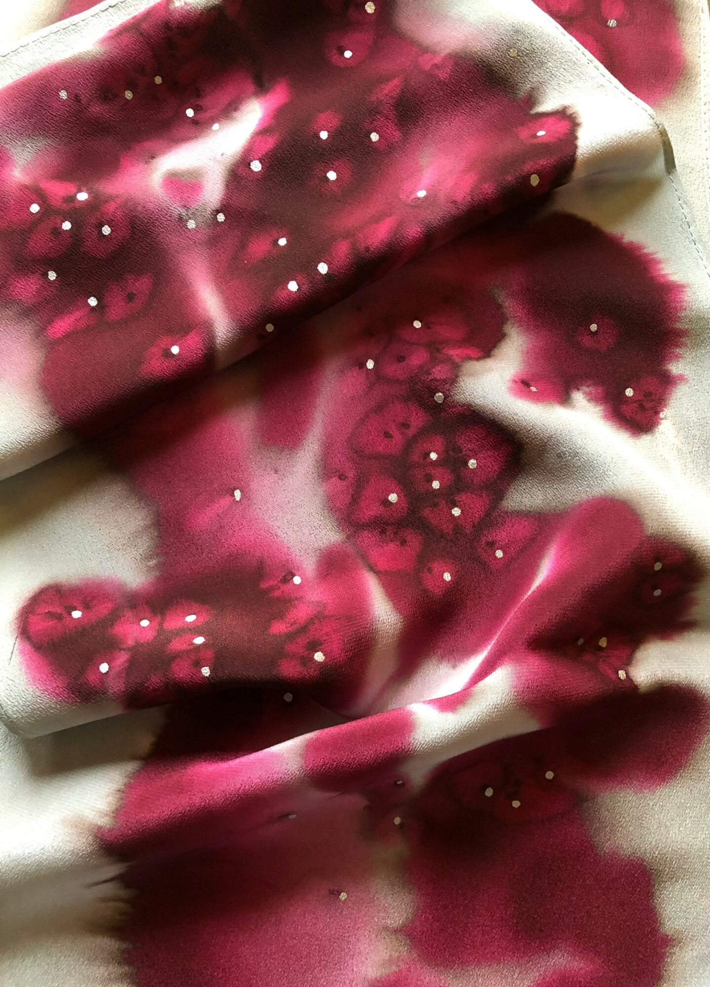 Fabric with pink and white watercolor-like pattern and small white dots, slightly crumpled.