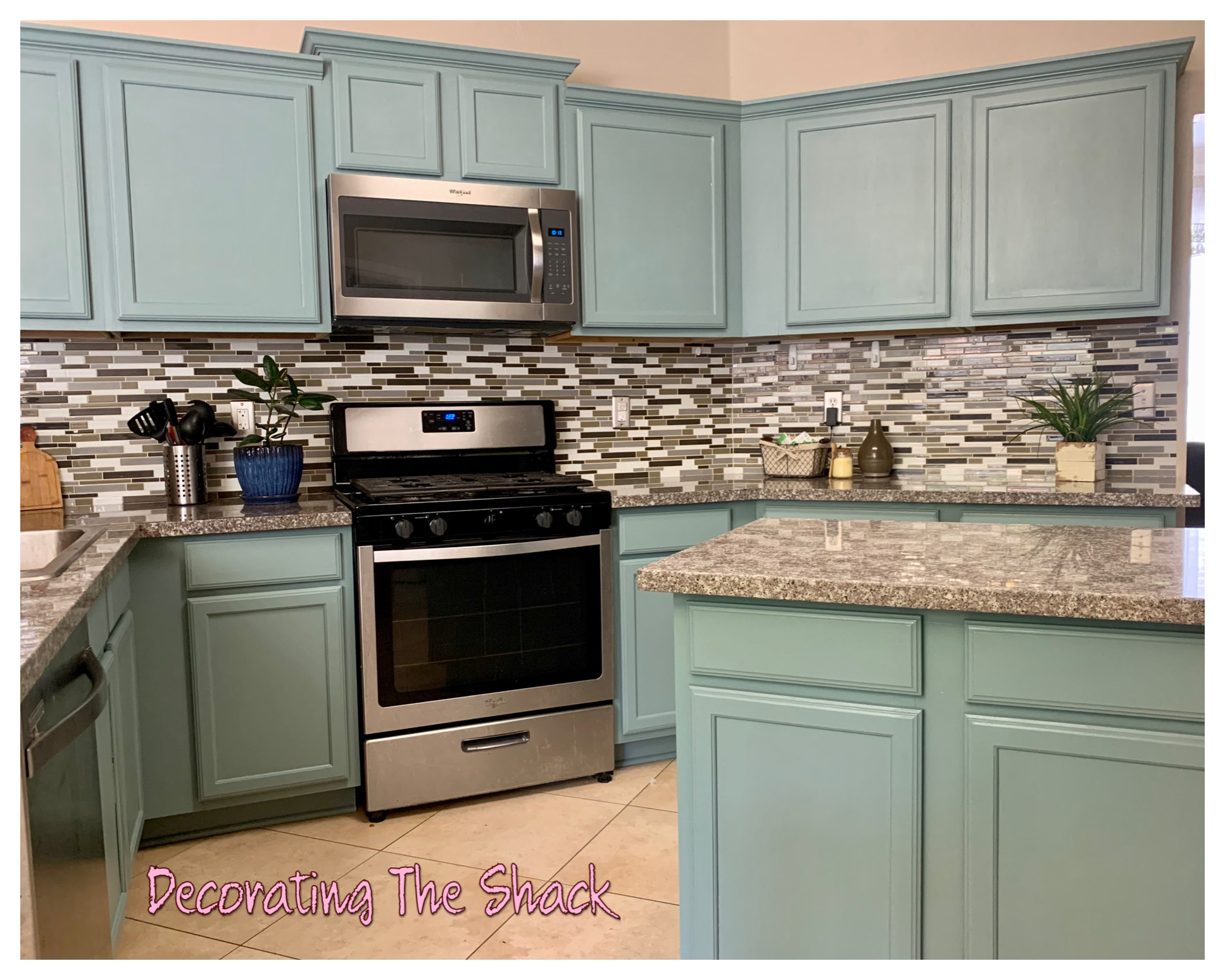 Kitchen with light blue cabinets, stainless steel stove, microwave, granite countertops, and a mosaic tile backsplash.