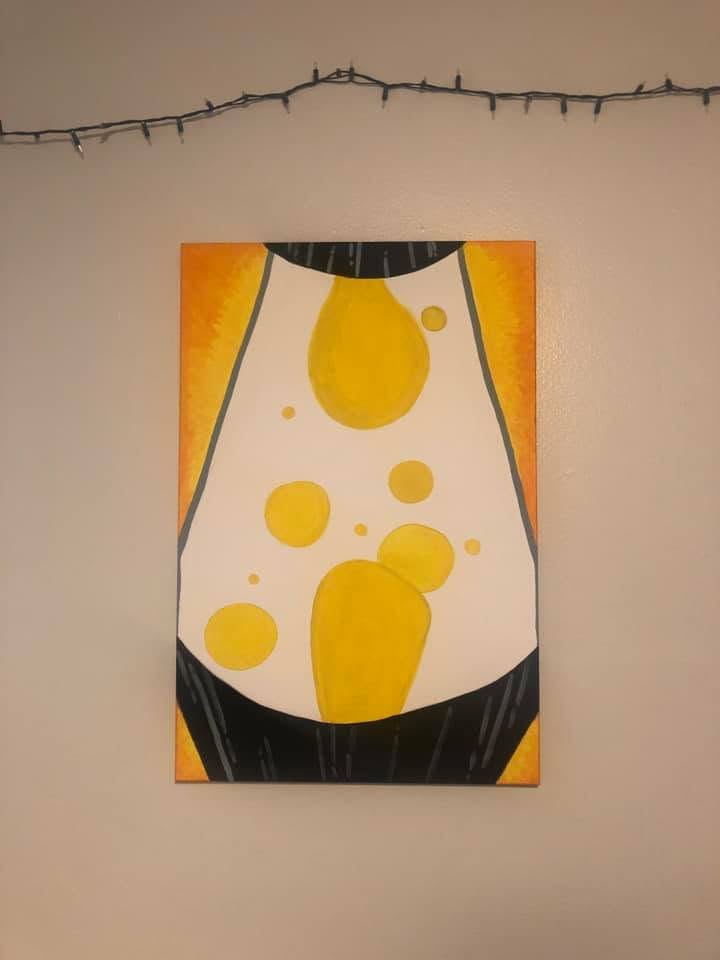 Abstract painting with yellow and black shapes on a white background, hung on a wall with string lights above.