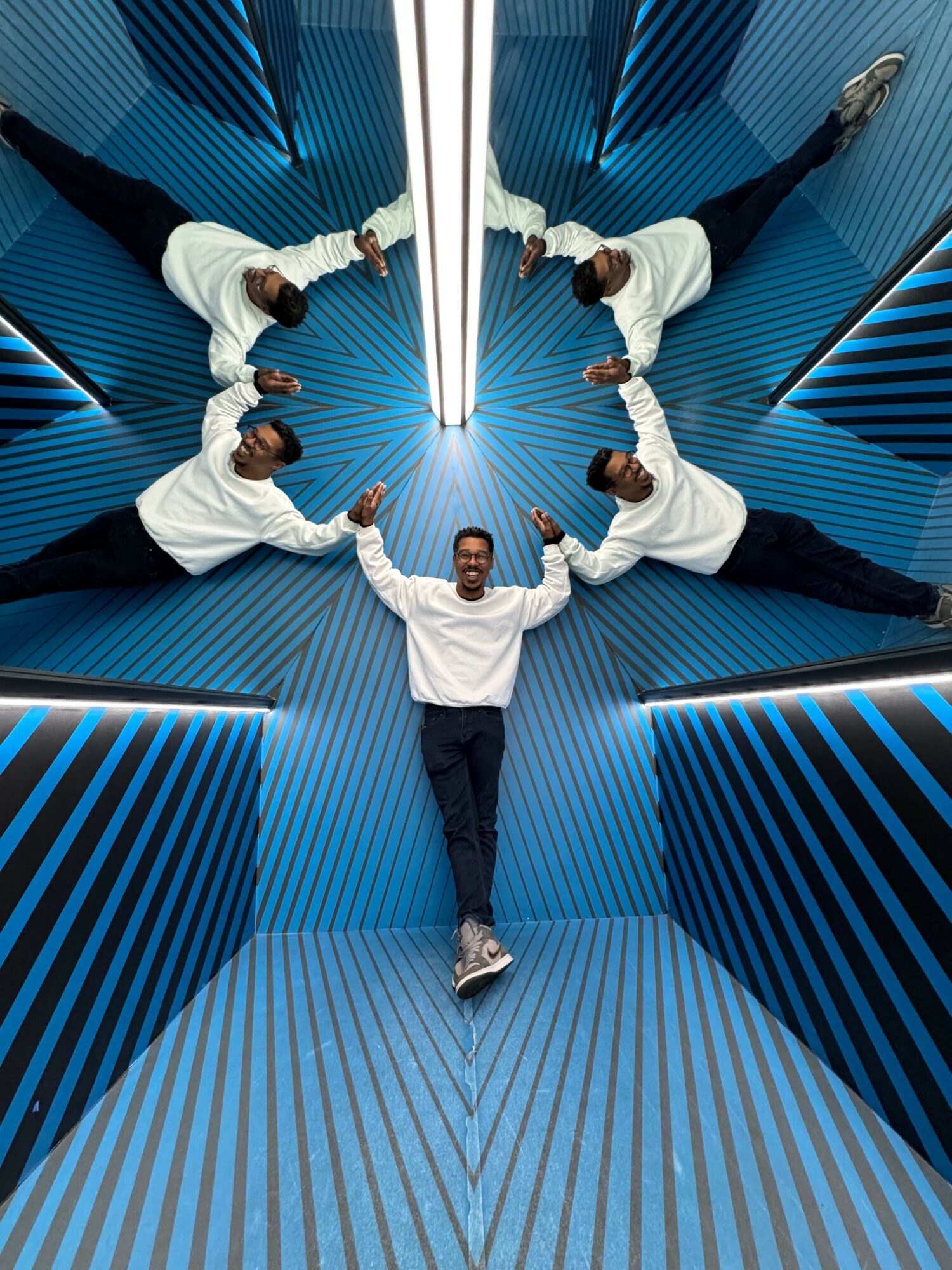 Five people lying on the floor in a circle, looking up, with blue striped walls and ceiling around them.