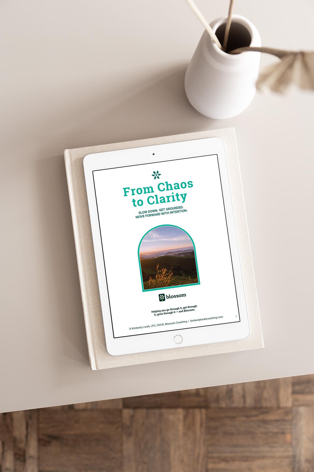 E-book titled 'From Chaos to Clarity' on a white tablet, placed on a white surface with a white vase nearby.