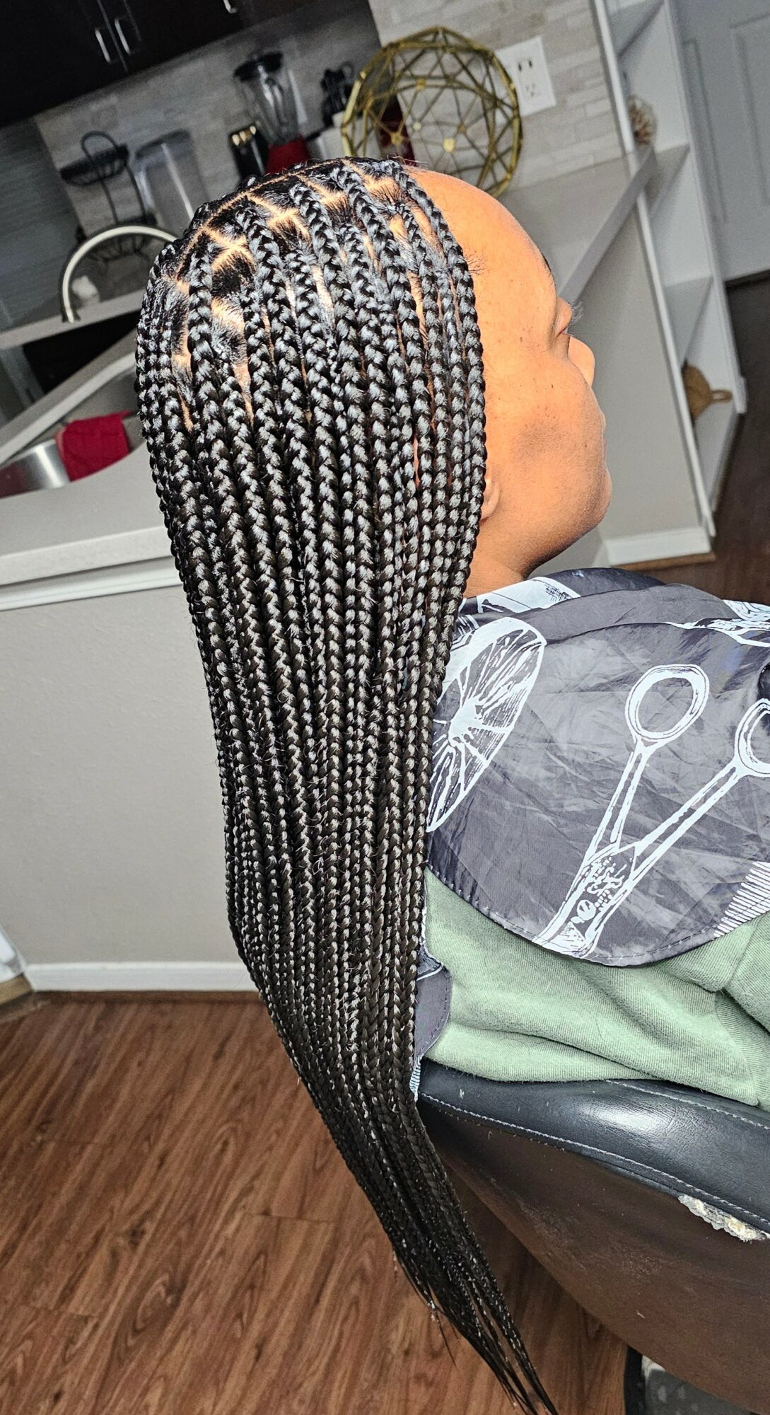 Side view of a mannequin with long, black and white braided hair, seated in a salon chair.