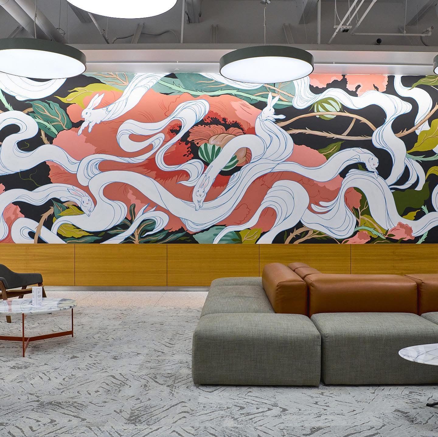 Colorful mural with swirling white, orange, and black shapes, and a seating area with gray and brown furniture.