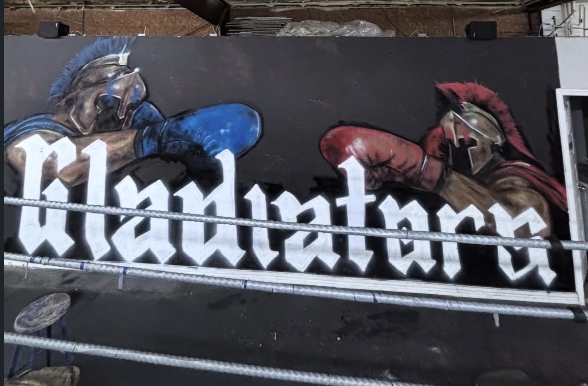 Graffiti mural of two boxing gloves facing each other with stylized text in black and white.