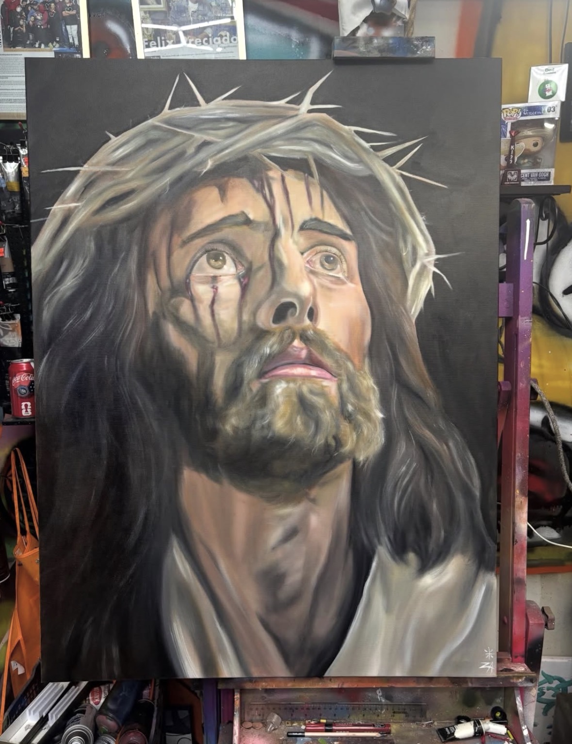 Painting of Jesus with a crown of thorns, looking upward with a somber expression, on a dark background.