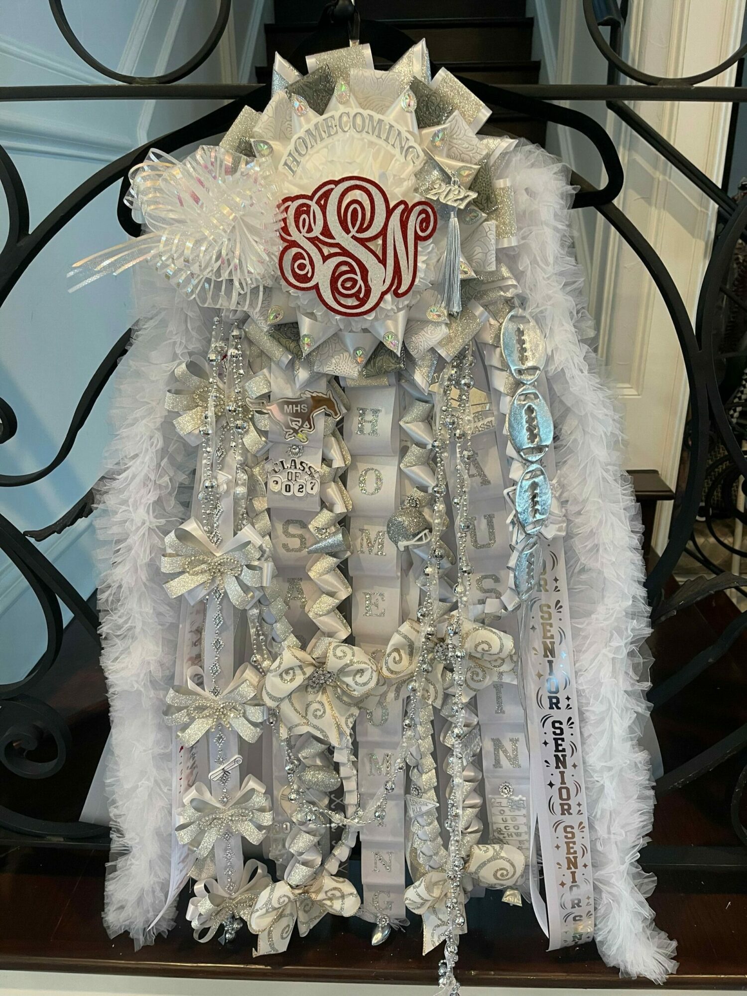 Decorative arrangement with white ribbons, bows, and a red swirl design on a white fluffy background.