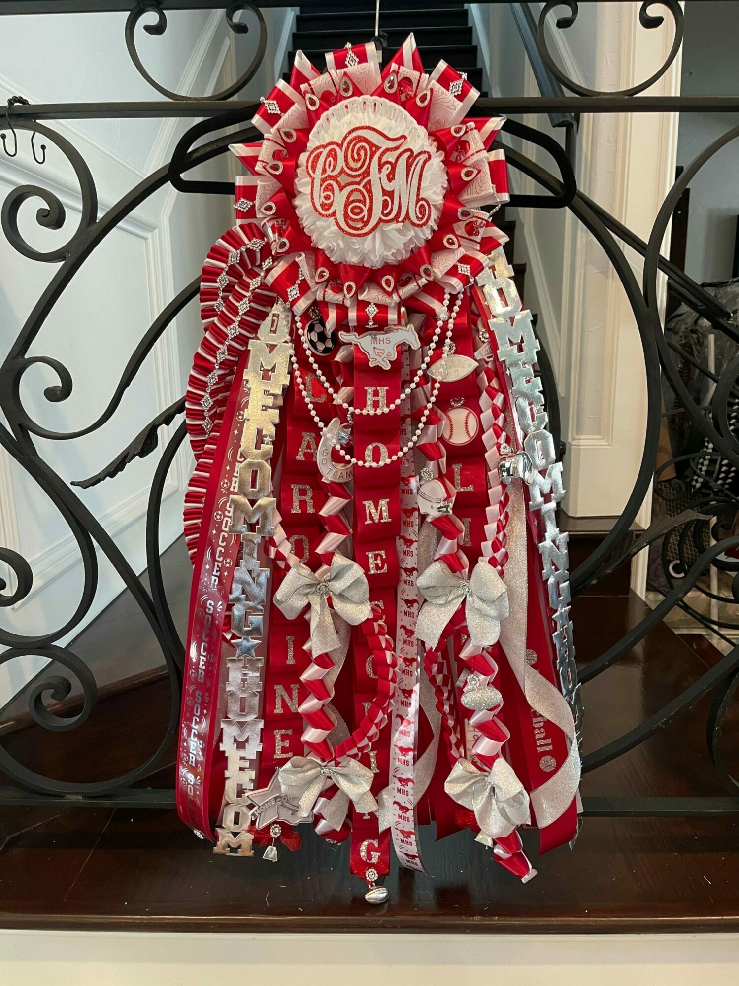 Decorative figure made from red and white candy wrappers, ribbons, and beads, resembling a festive character or doll.