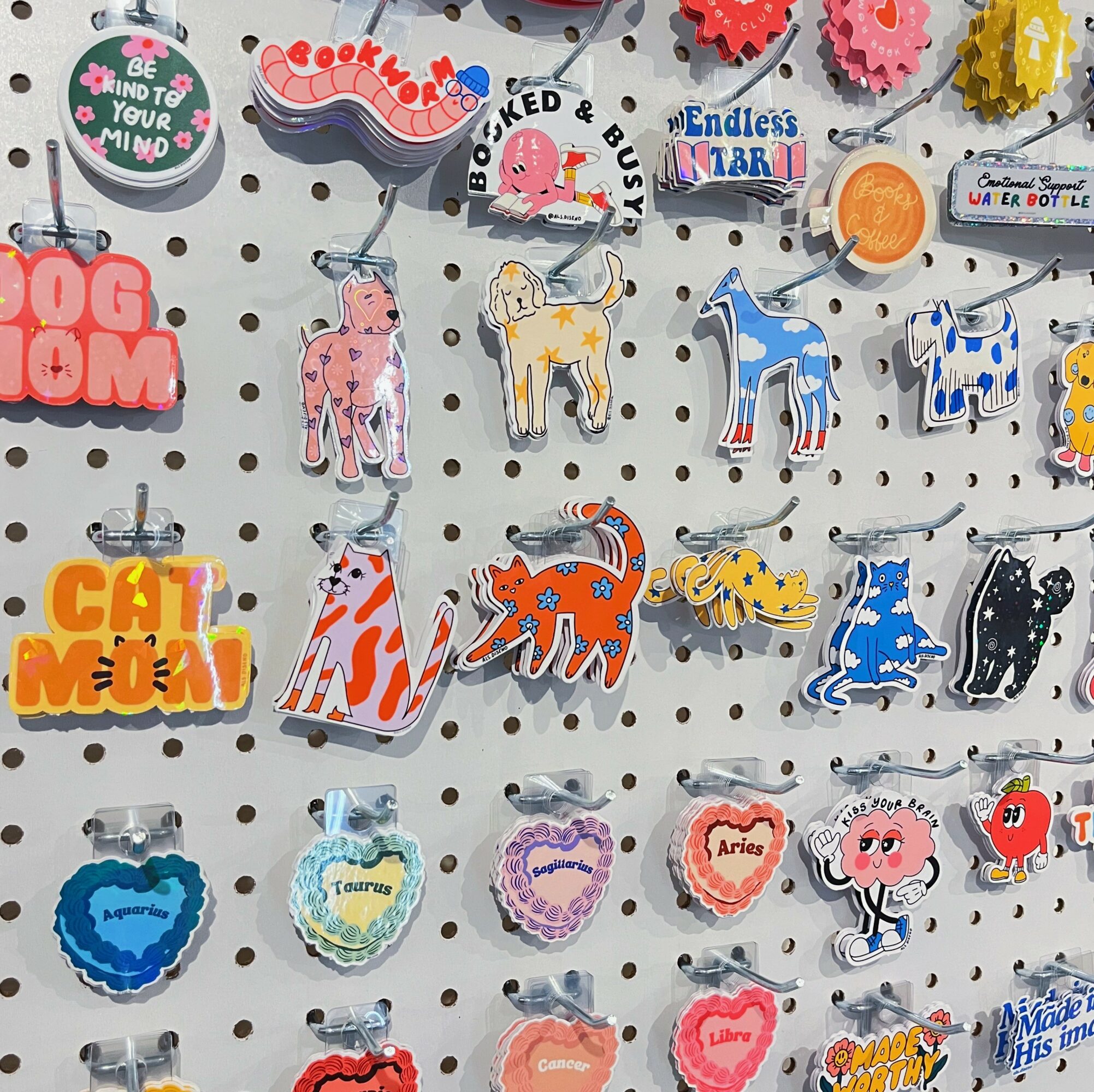 Colorful animal and message keychains hanging on a display board with various designs and texts.