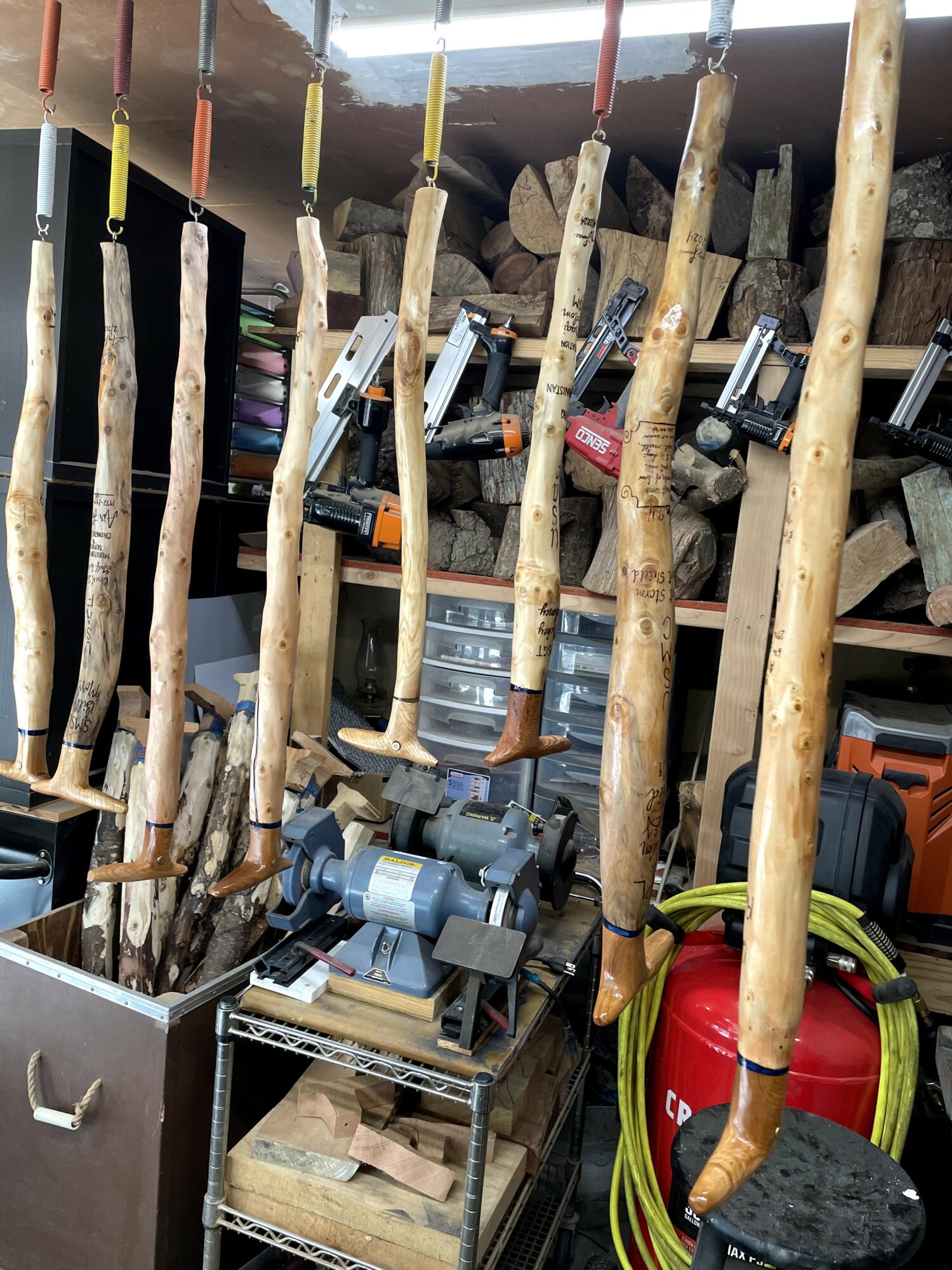 Wooden sticks and tools hanging in a workshop, with shelves and equipment in the background.
