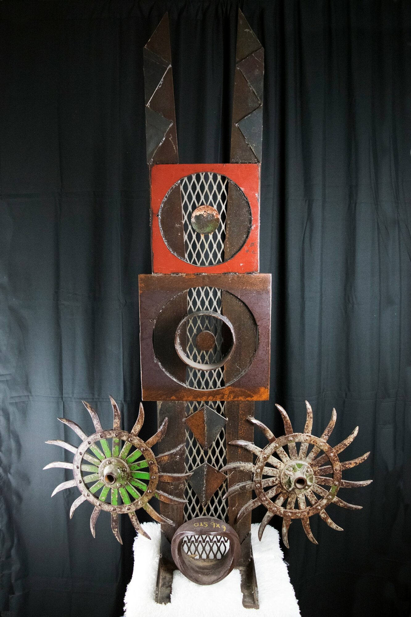 Display of three decorative circular objects with spiked edges and a central patterned piece, set against a black curtain background.
