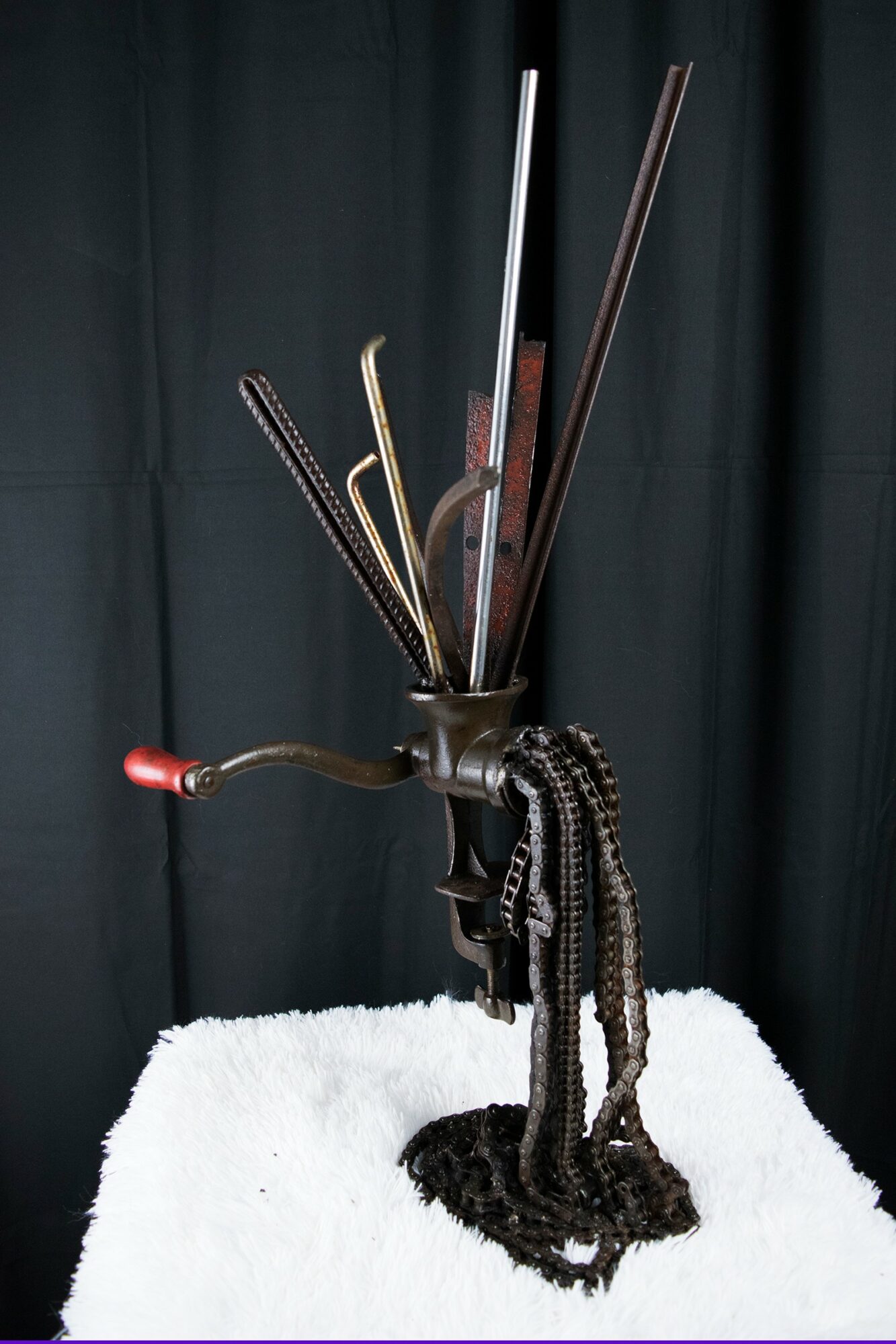 A holder with various metal and wooden sticks, some with curved ends, against a dark background, with a white surface below.