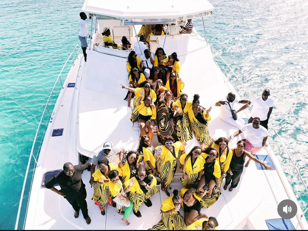 Group of people on a boat, some wearing yellow clothing, with water in the background.