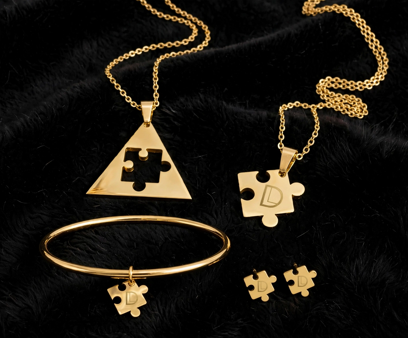 Gold jewelry set with puzzle piece pendants, including a necklace, bracelet, and earrings, displayed on black fabric.