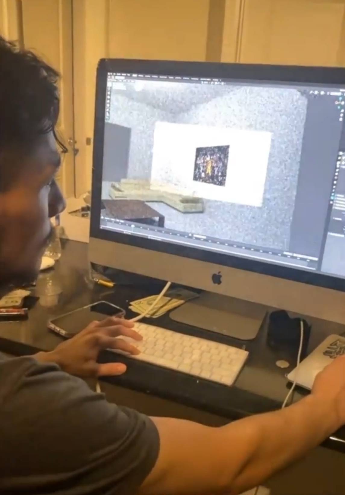 Person working on computer with a design project visible on screen, in a room with yellow walls.