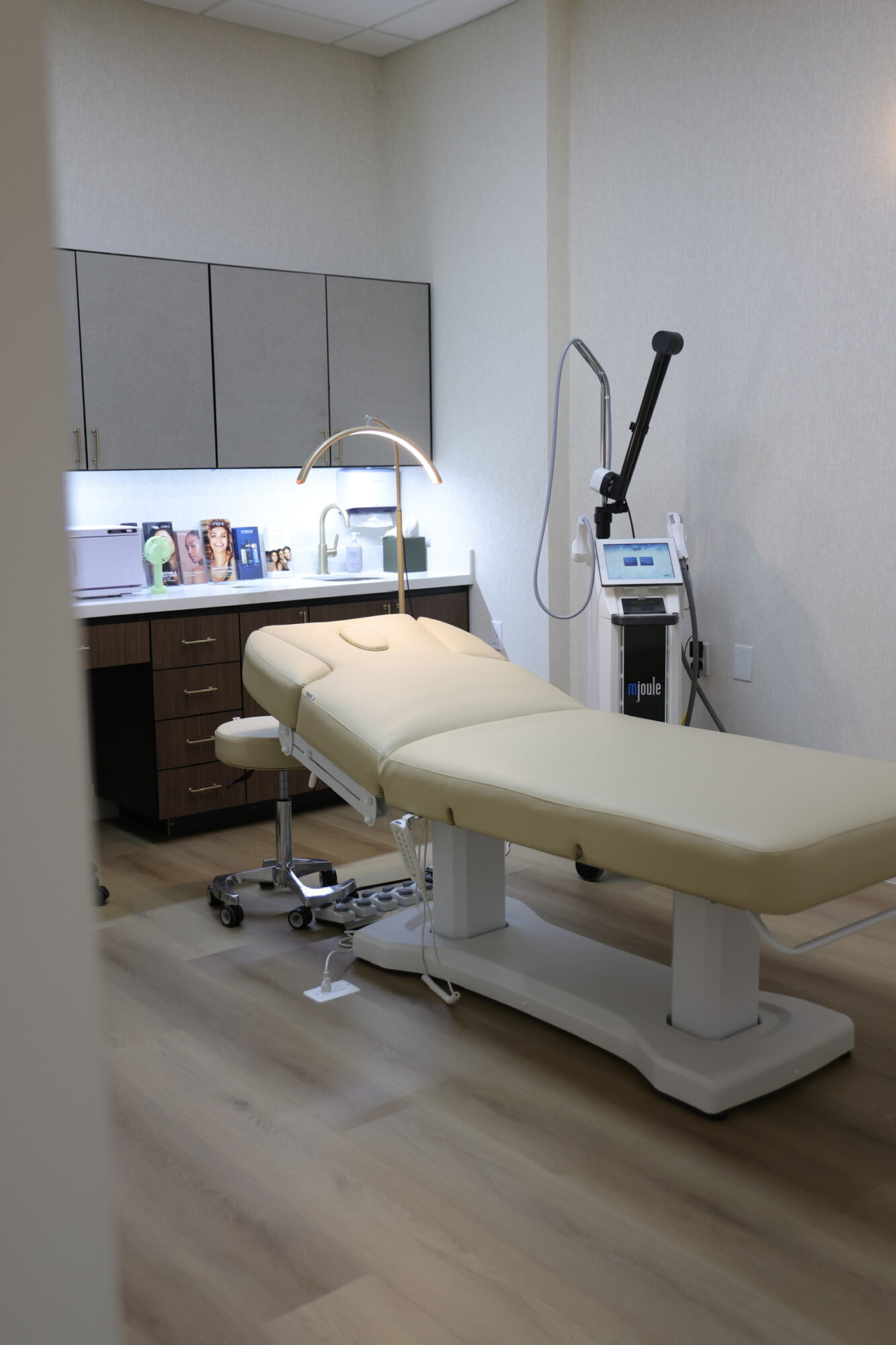 Medical examination room with an adjustable examination table, sink, and medical equipment against a wall.