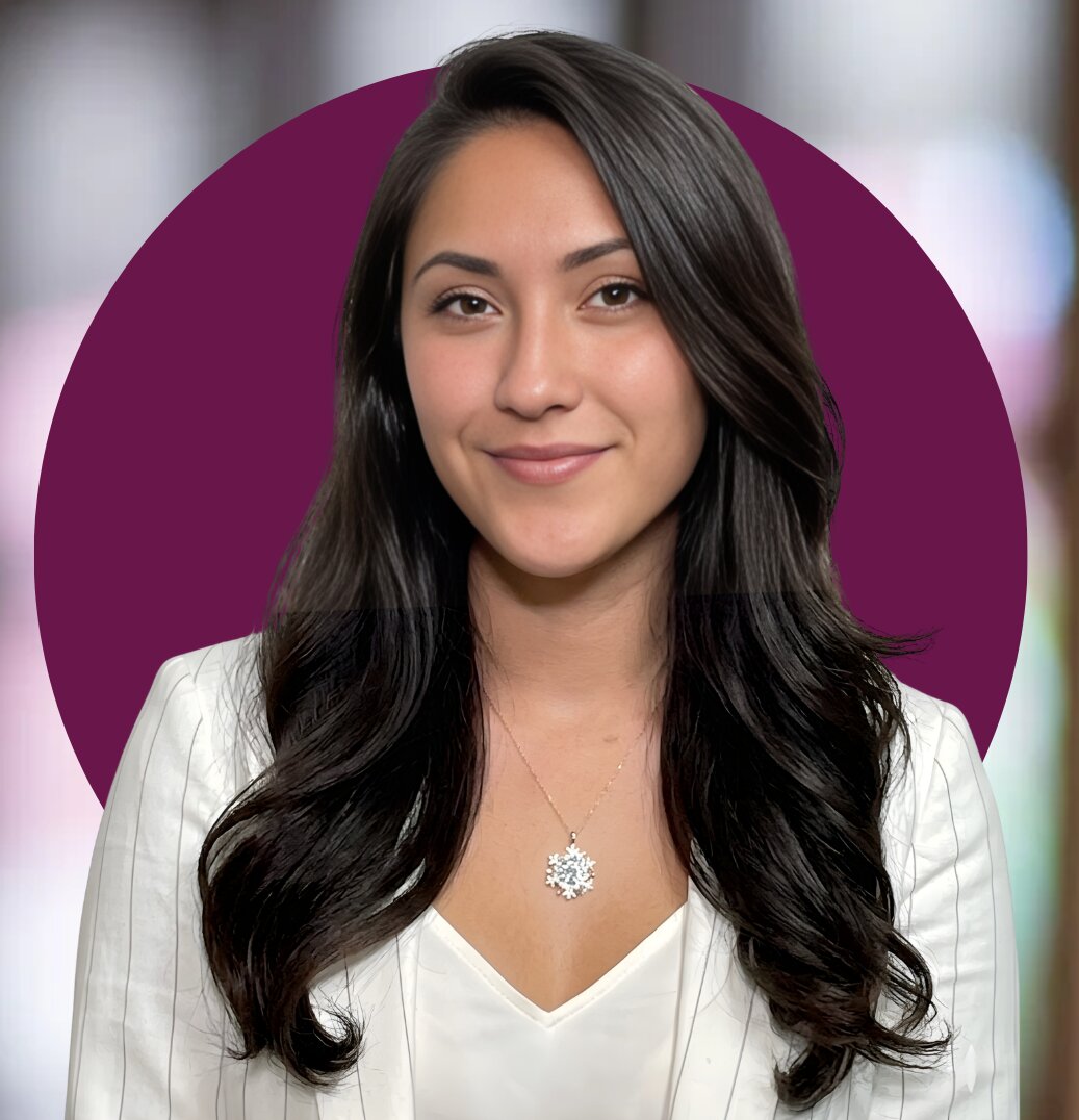 Portrait of a woman with long dark hair, smiling, wearing a white blazer and necklace, against a purple background.