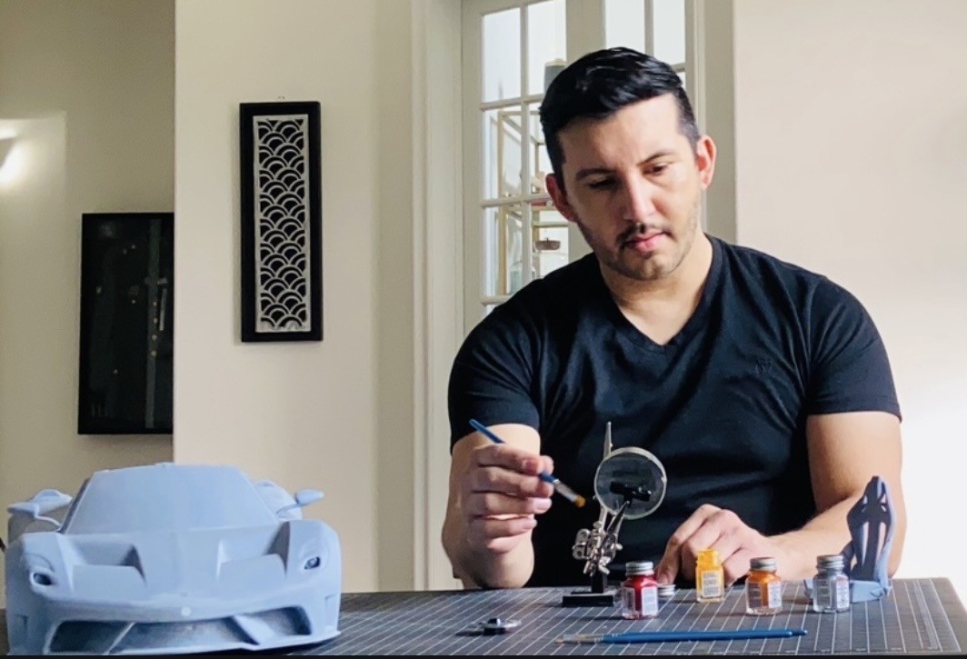 Man playing a tabletop game with miniature figures, sitting at a table in a bright room.