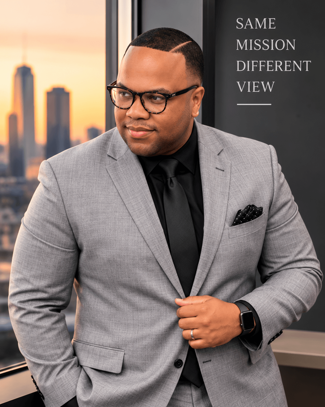 Man in gray suit and glasses standing indoors with city skyline in background, looking to the side.